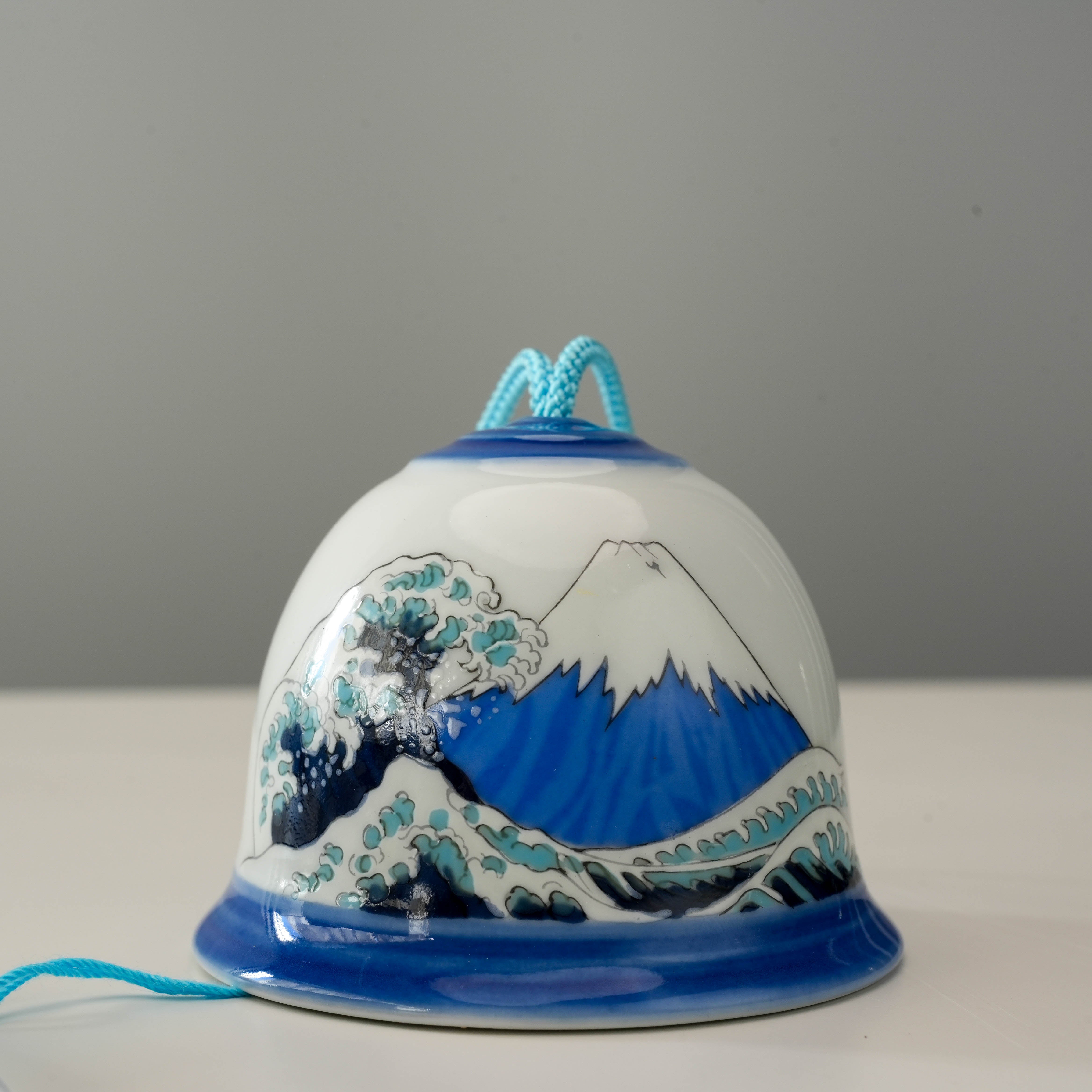 Detailed view of Arita Ware Wave Fuji Mt Wind Chime, showing traditional Japanese design with Mt. Fuji and ocean waves in blue and white.
