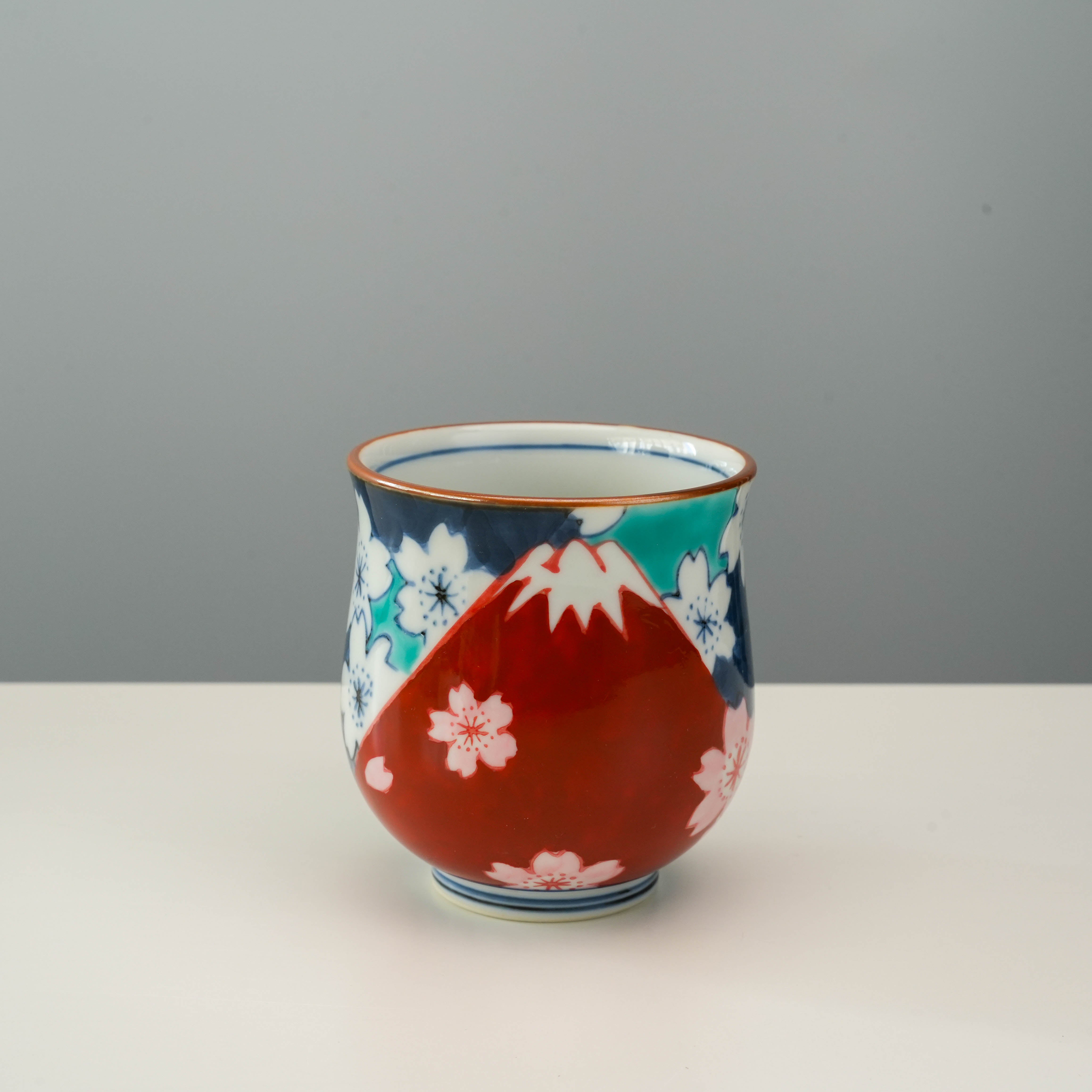 Arita Ware Cup featuring Mt Fuji and Sakura blossoms in vivid red, blue, and white tones. Elegant Japanese design ideal for tea lovers.