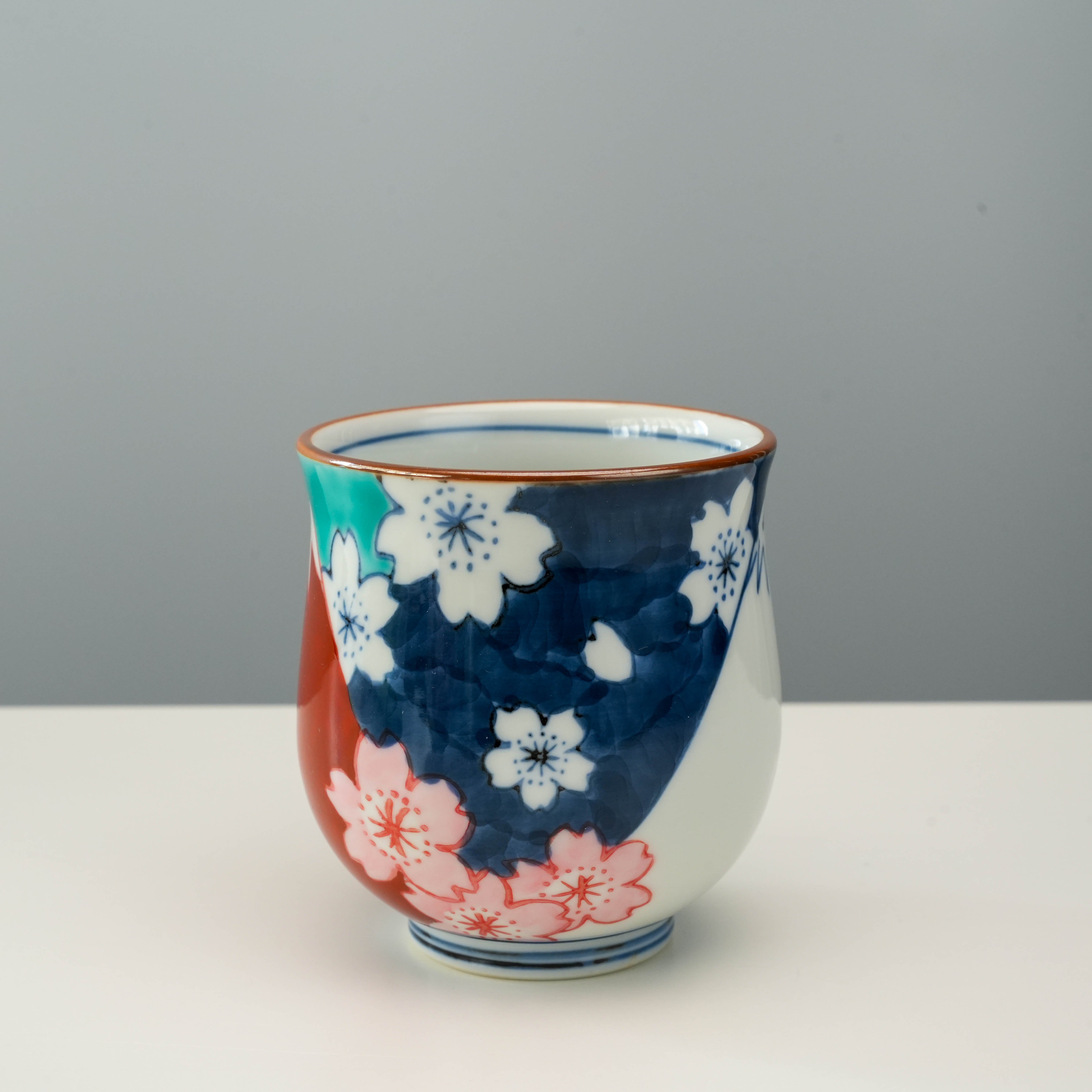 Japanese Arita Ware tea cup with hand-painted cherry blossoms and Mt Fuji motif. A refined decor piece for tea ceremonies or display.
