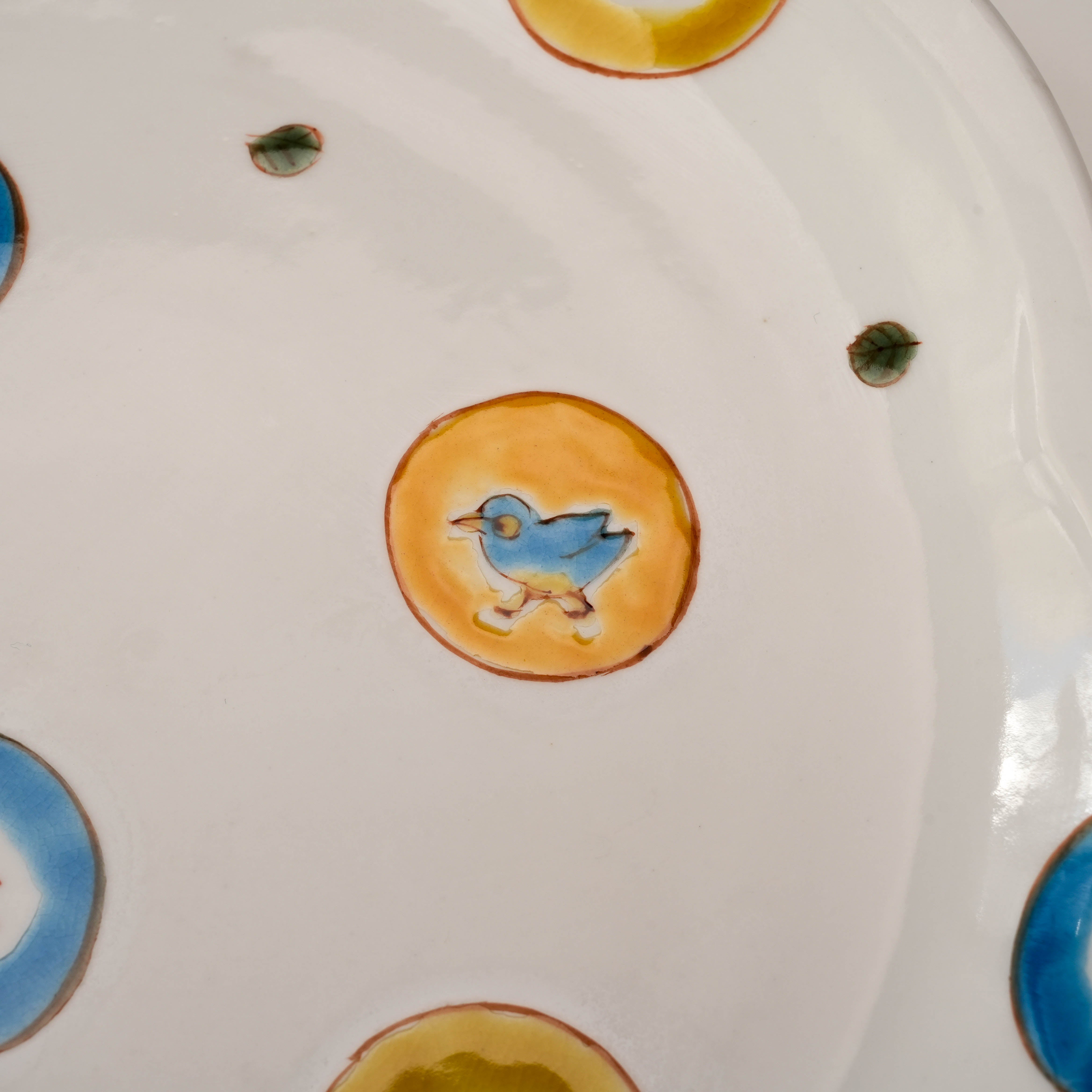 Detail of Kutani Ware Serving Plate – Marumon Mizutama featuring a walking blue bird in orange circle. Fine ceramic dinnerware with playful design.
