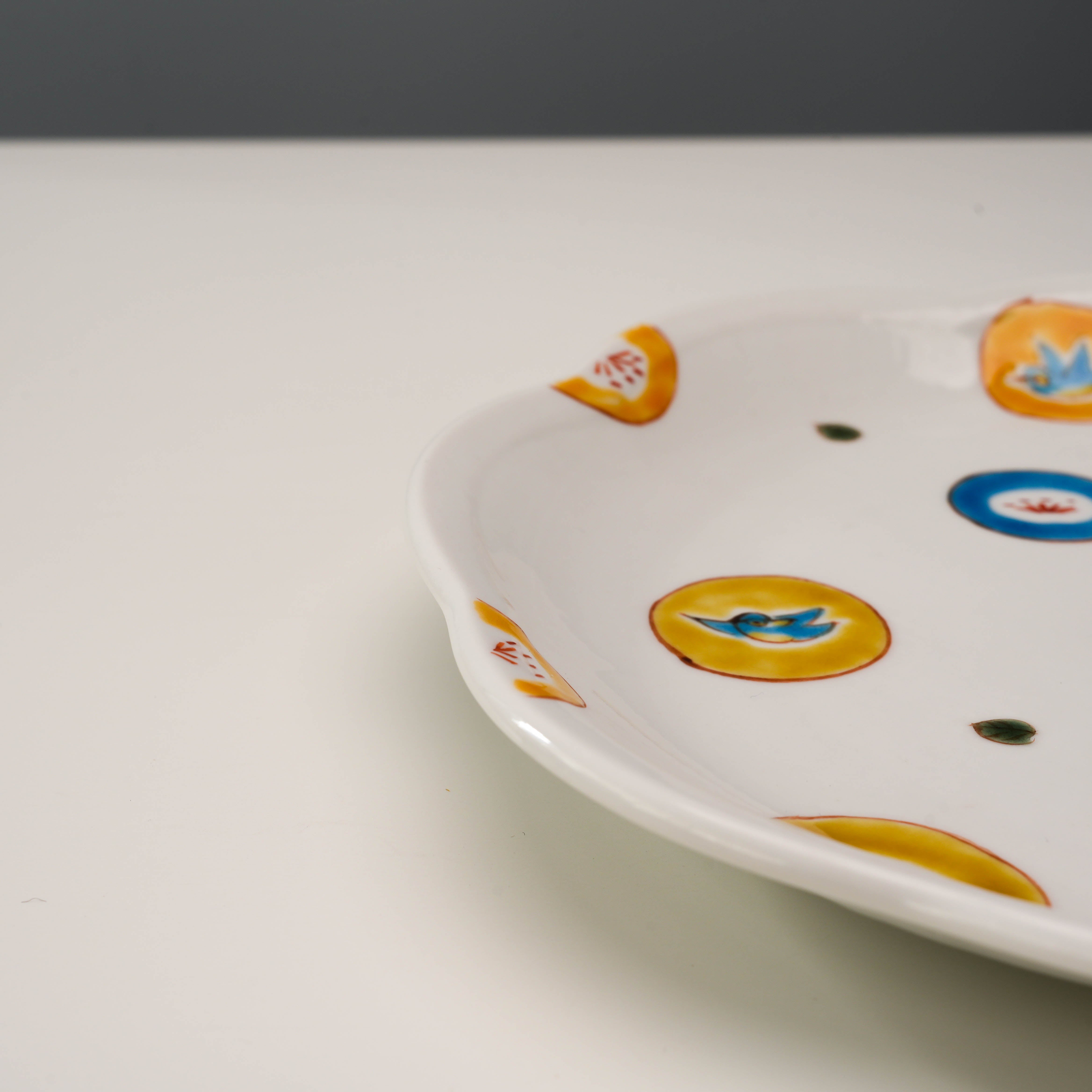 Side view of Kutani Ware Serving Plate – Marumon Mizutama highlighting its curved rim and vibrant hand-painted accents. Elegant Japanese dinnerware piece.