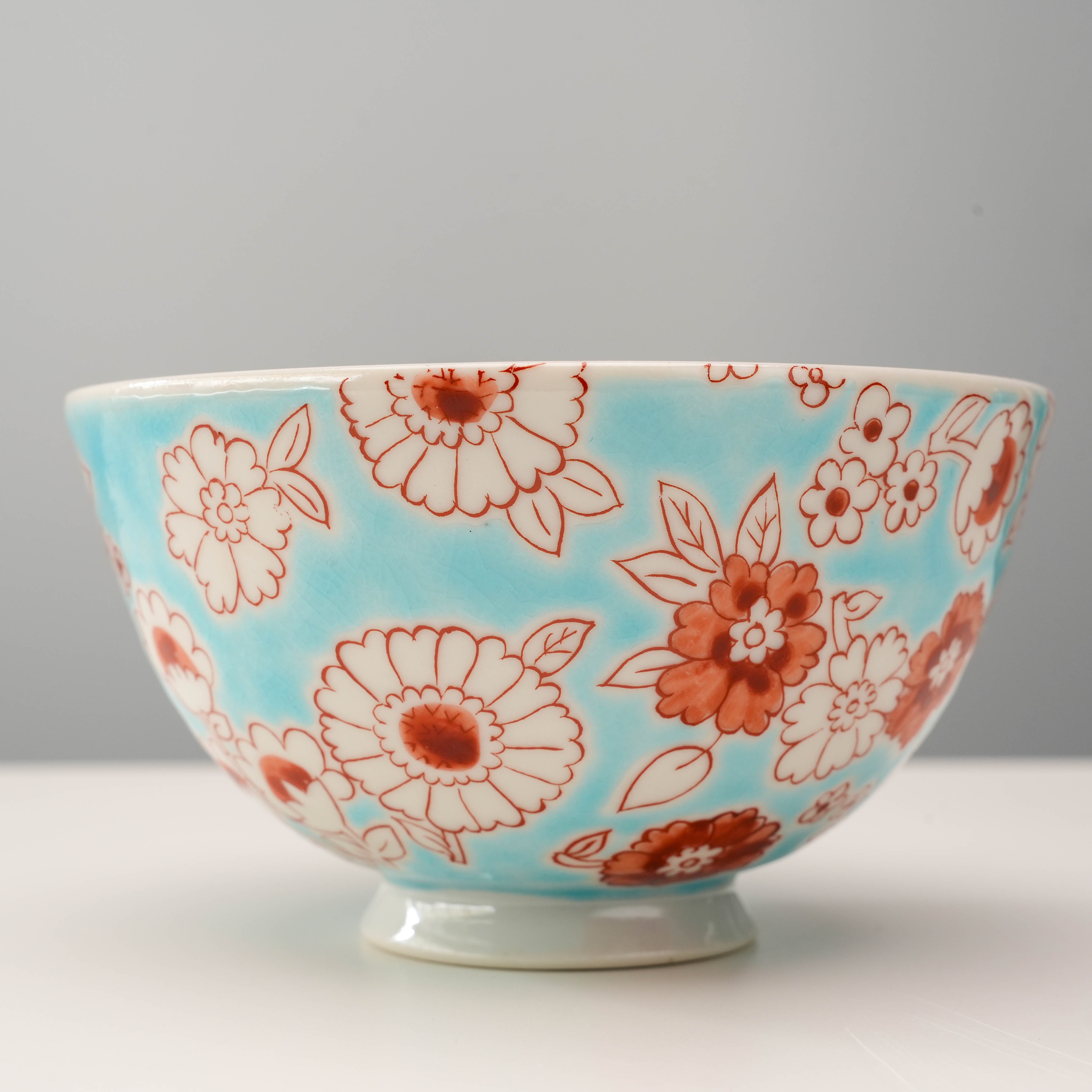 Close-up of Flower Shower Kutani Rice Bowl showcasing detailed red floral motifs on glossy blue porcelain, combining beauty and function.