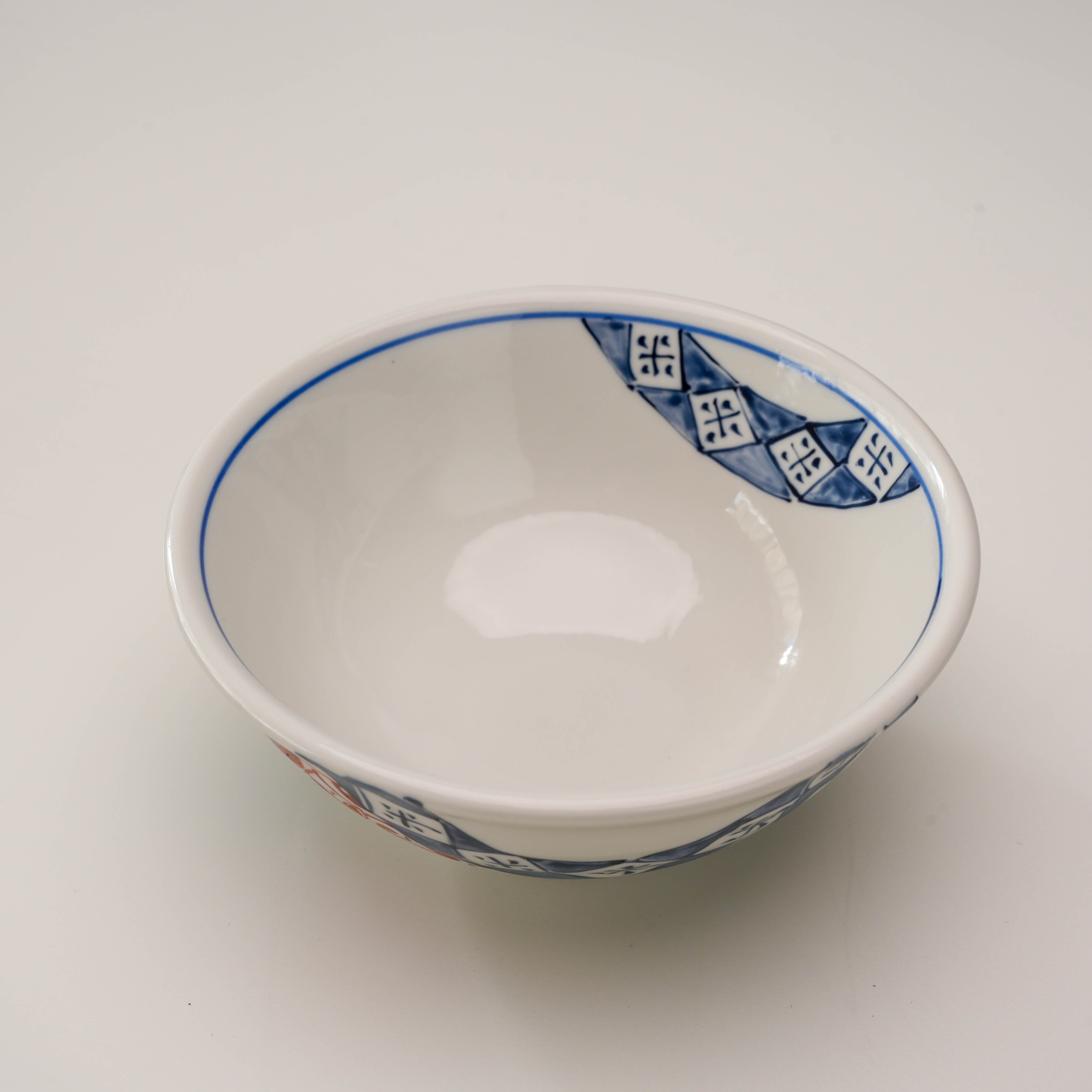 Top view of Kutani Rice Bowl - Hanamaru Pattern with glossy white interior and blue geometric rim, blending function with traditional artistry.