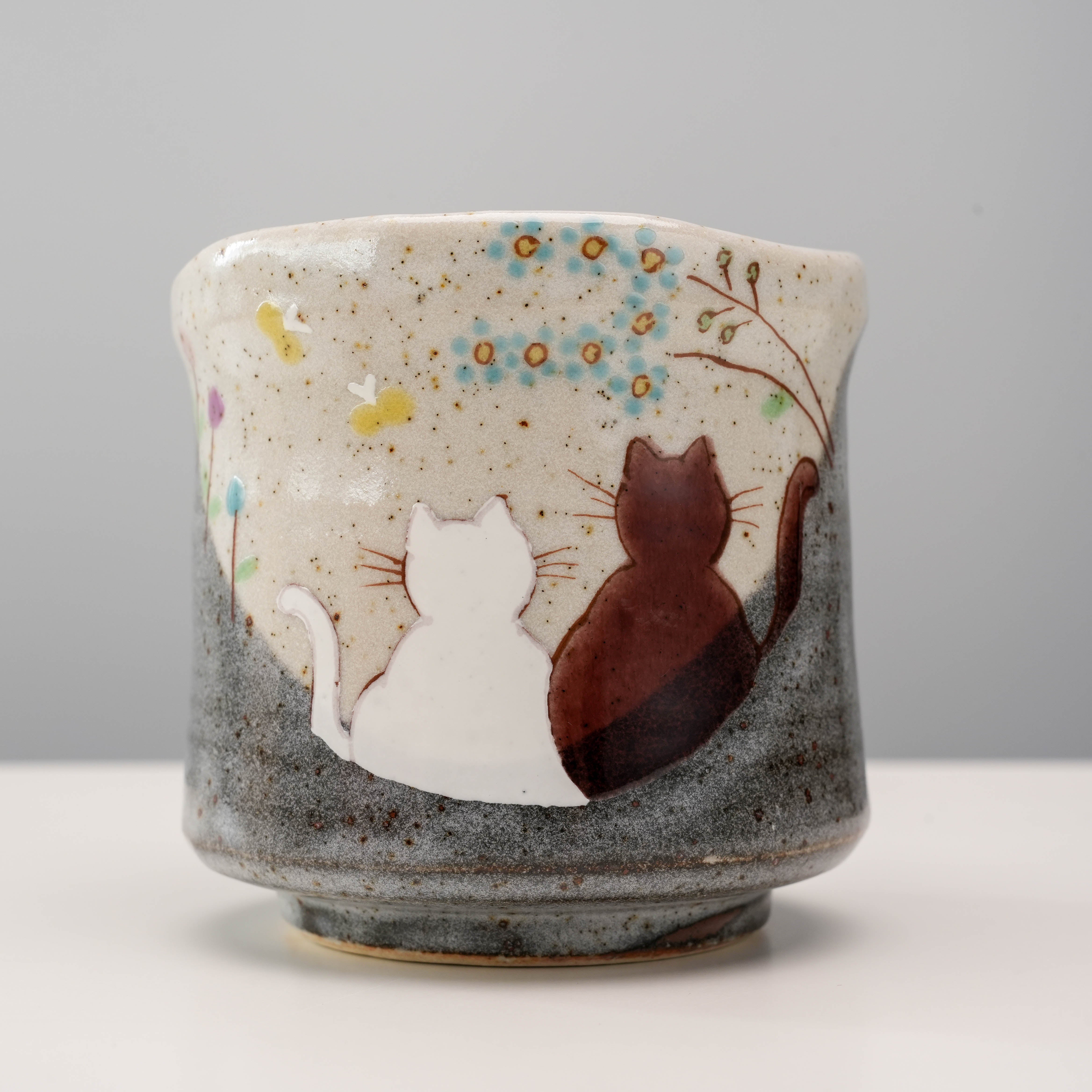 Close-up of Kutani Cat Yunomi Teacup showing detailed white and brown cats under a blooming tree. A whimsical addition to dinnerware collections.