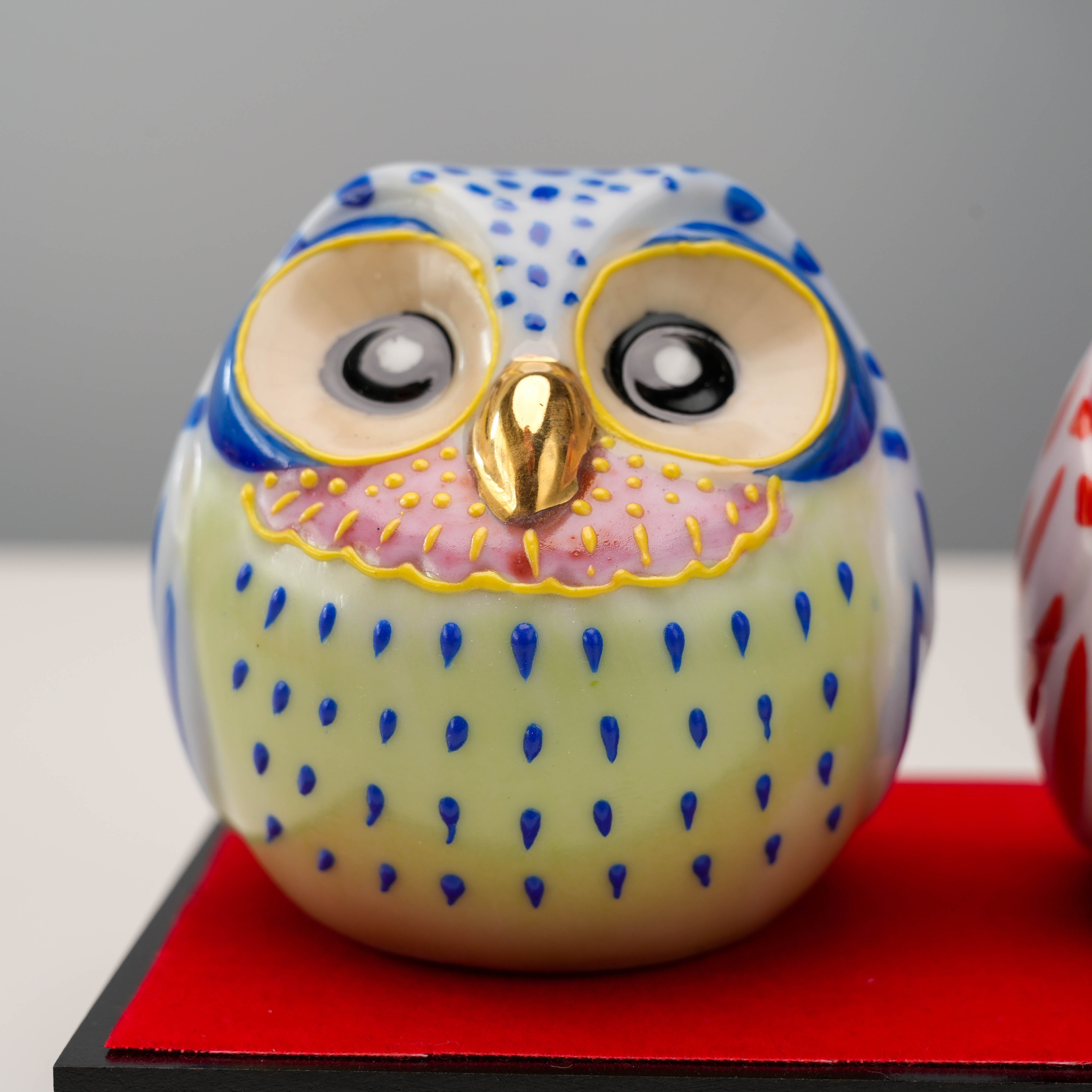 Close-up of blue Kutani owl figurine with pink chest and golden beak. Hand-painted lucky ornament perfect for gifting or decorating.