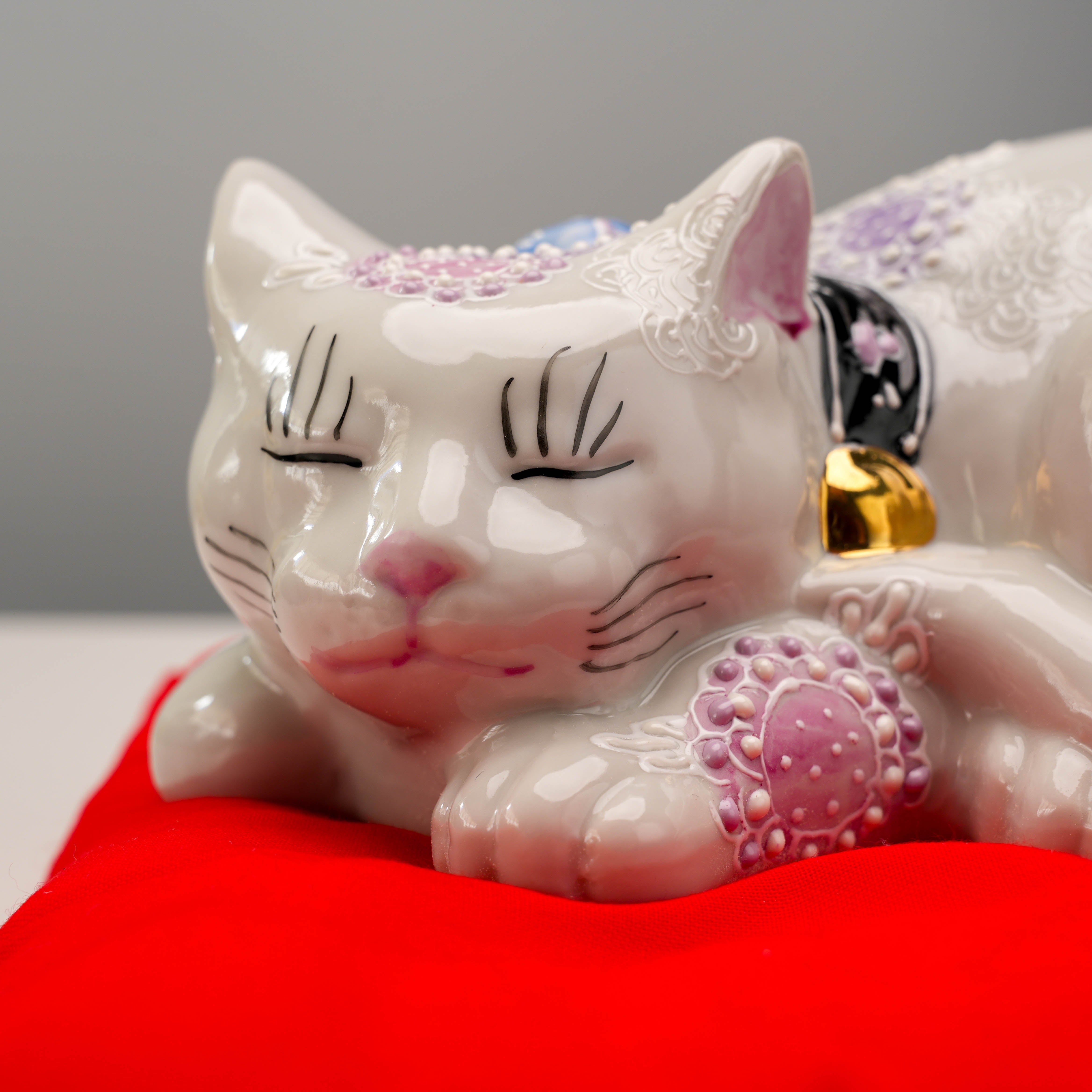 Close-up of Kutani Ware Sleeping Cat ornament showing detailed facial features and golden bell, a serene lucky cat decor piece.
