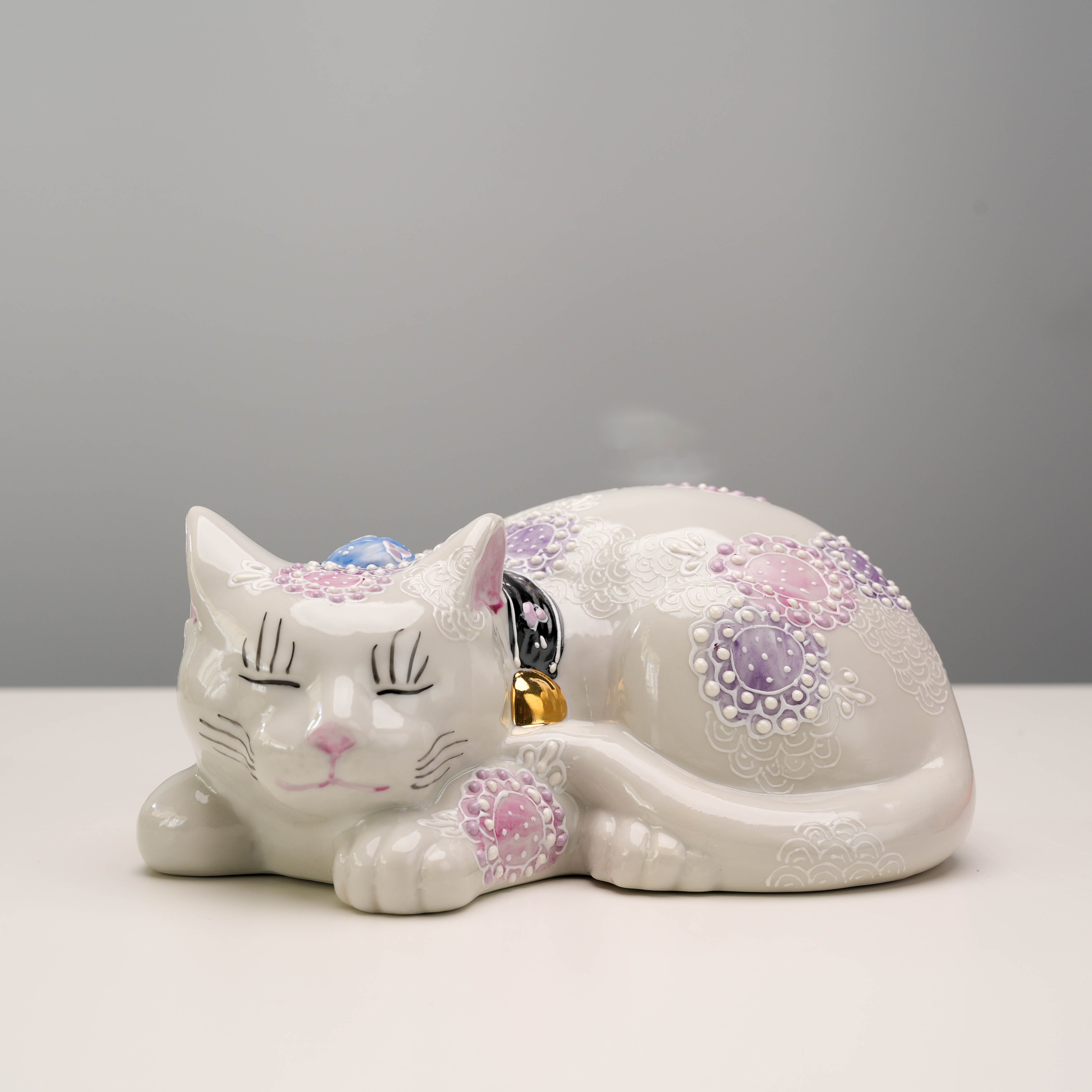 Front-facing Kutani Ware Sleeping Cat - Lucky Cat with purple floral accents, a peaceful ceramic figurine for home and garden decor.