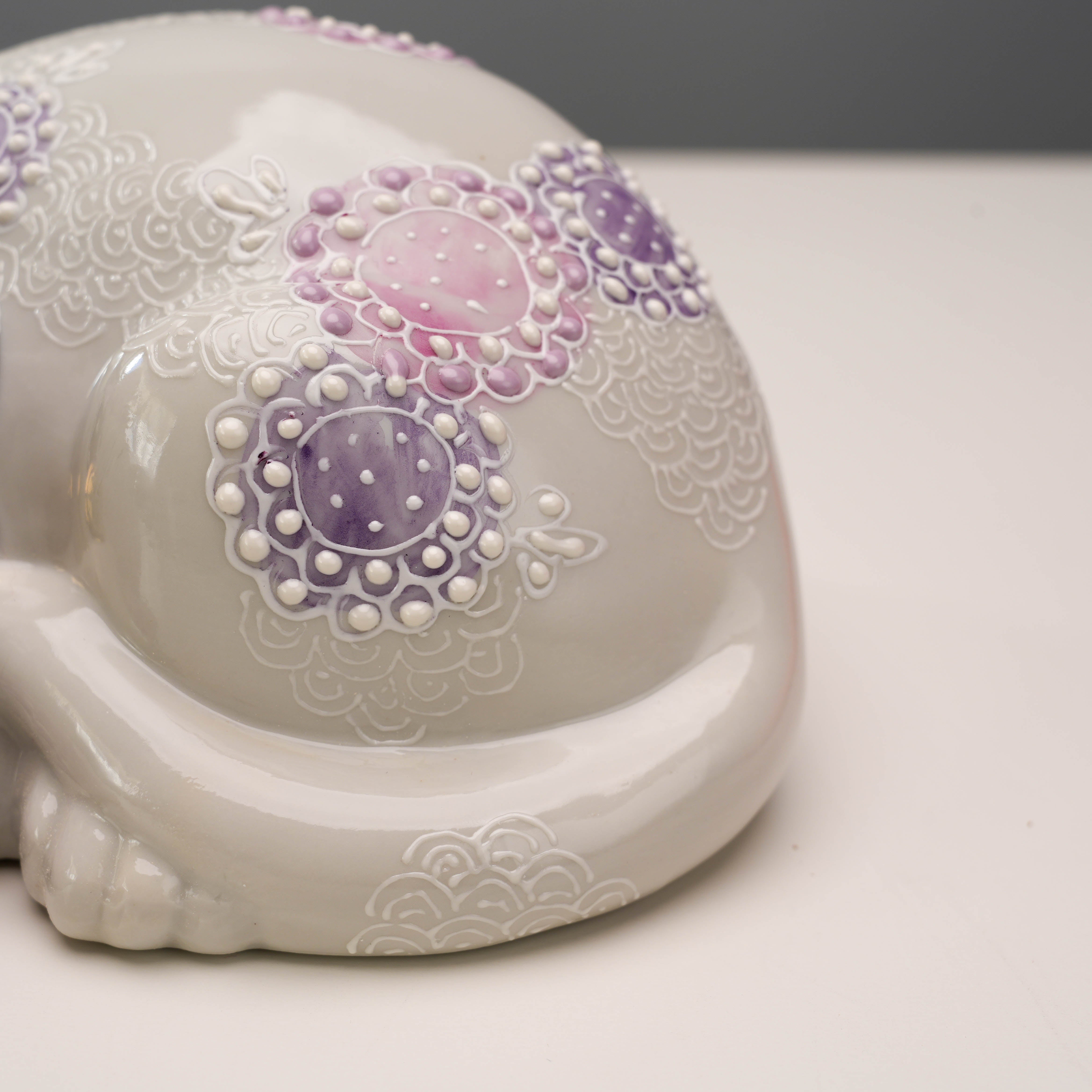 Detail shot of Kutani Ware Sleeping Cat's tail and floral pattern, showcasing craftsmanship in this decorative lucky cat figurine.