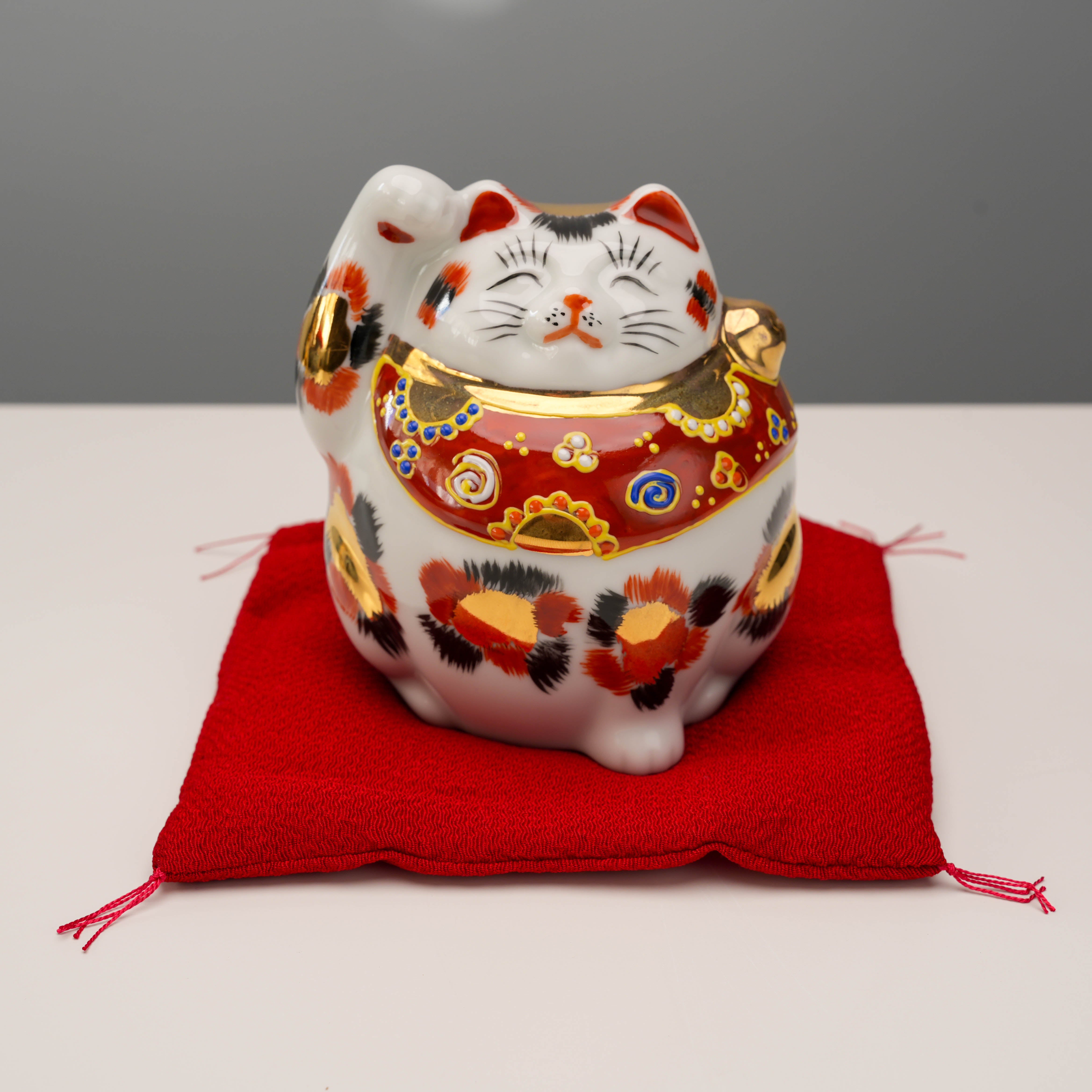 Front view of Kutani Ware Cat – Lucky Calico with raised paw and golden accents, a decorative figurine for good fortune.
