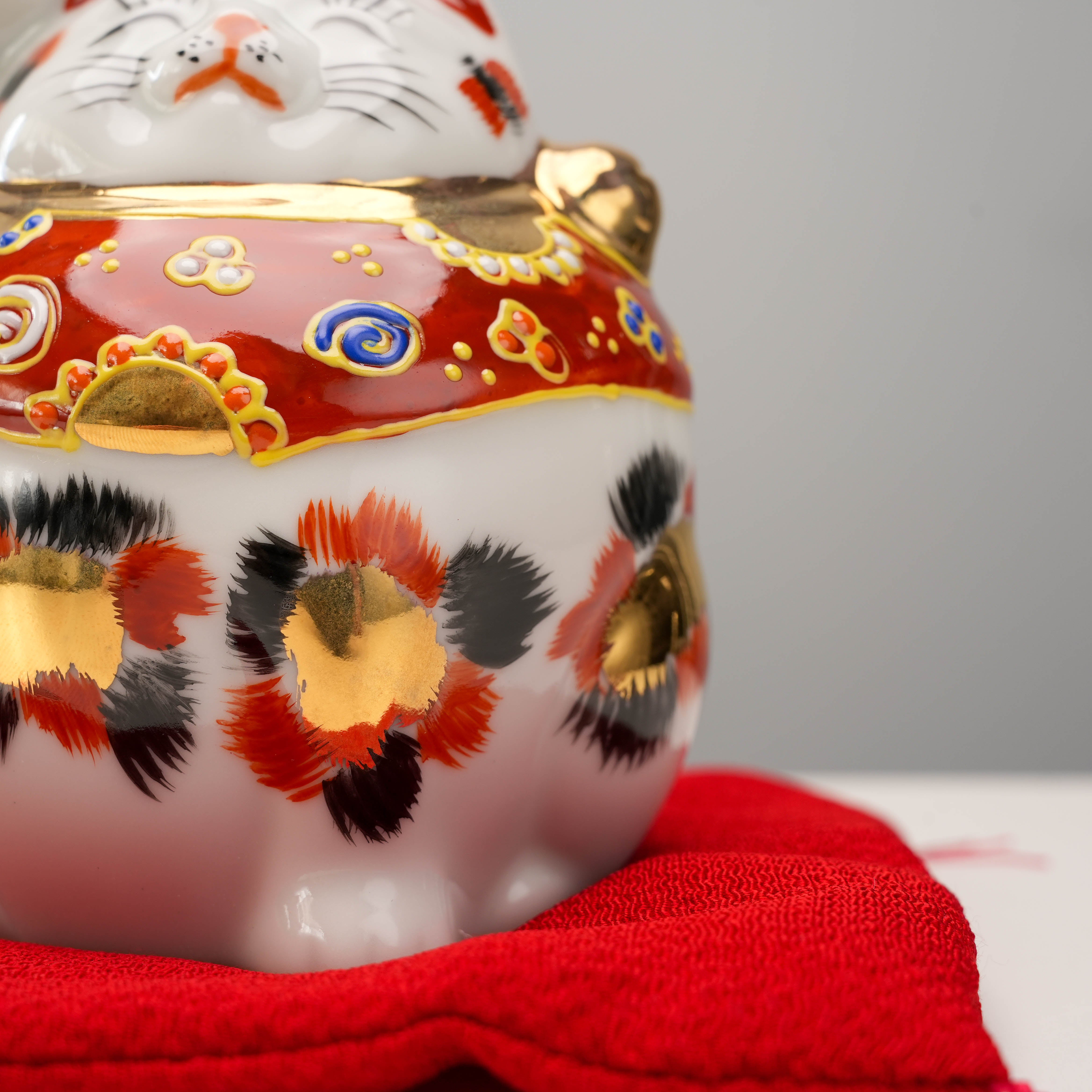 Detail of Kutani Ware Cat – Lucky Calico's gold and black floral spots and red cushion base, perfect for home decor charm.