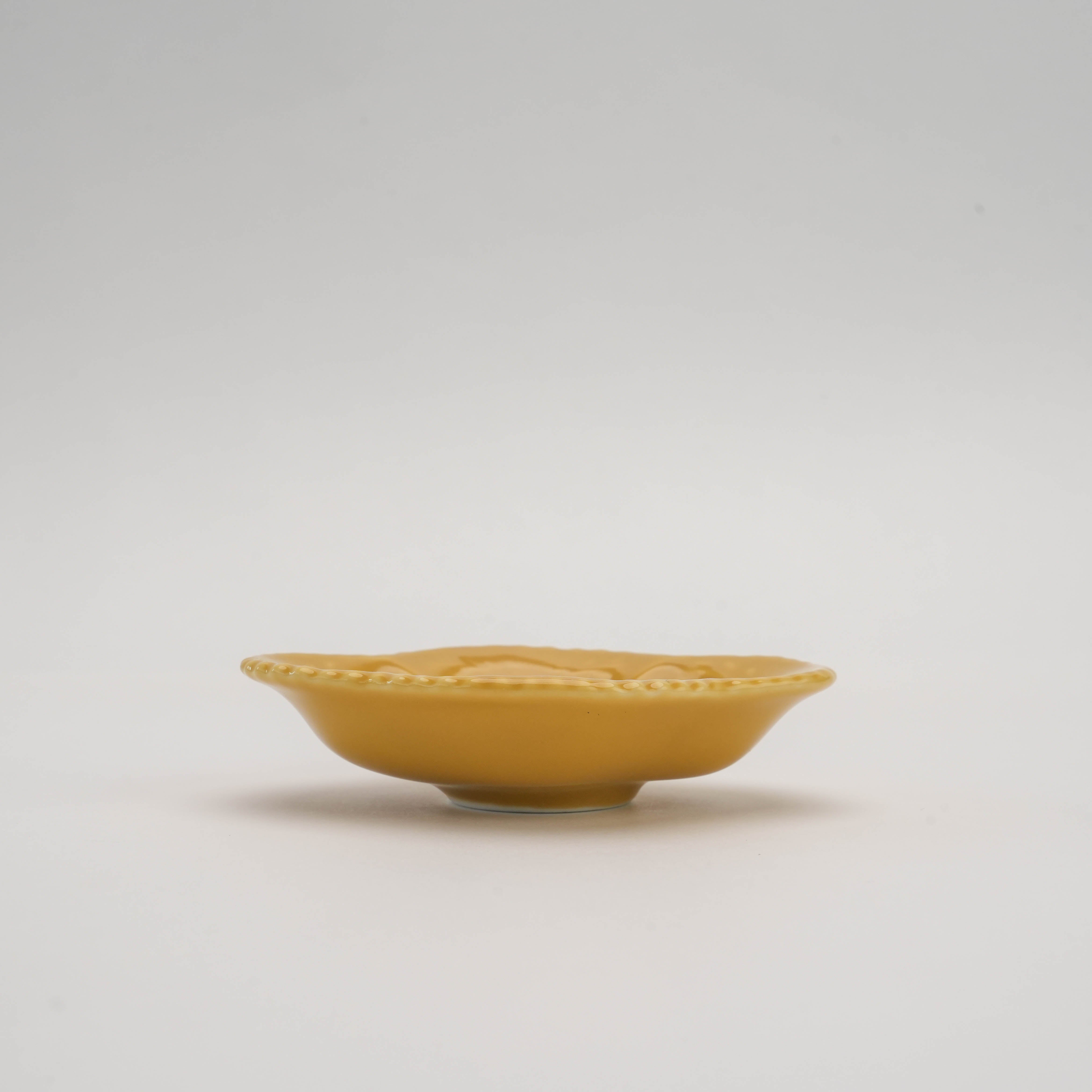 Side view of yellow Arita Ware Quince Dish highlighting its smooth glaze and elegant silhouette. Adds a pop of color to any dining setting.
