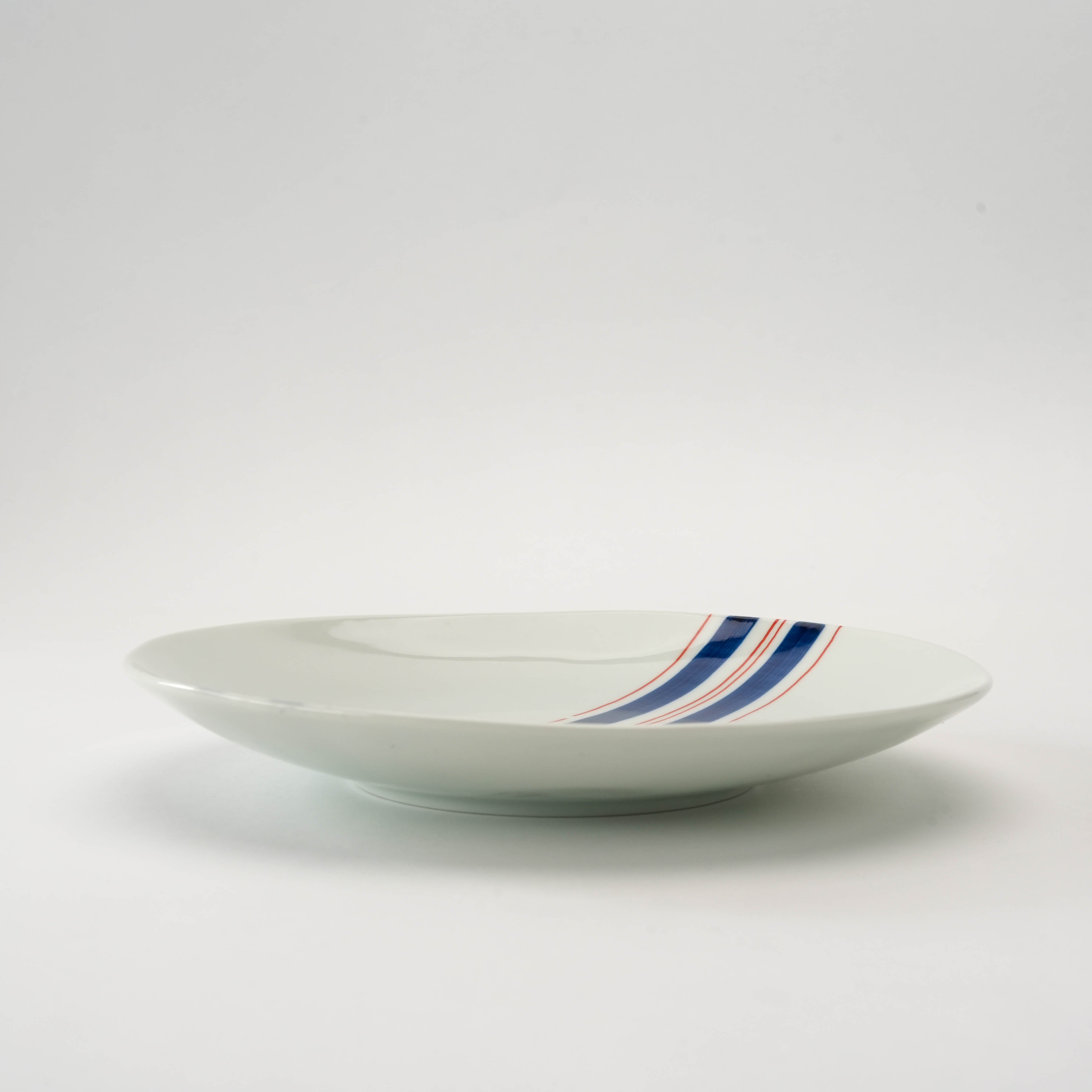 Side view of Arita Ware Obi-Tokusa Stripes Medium Plate, highlighting its shallow depth and elegant curved edge for stylish table settings.