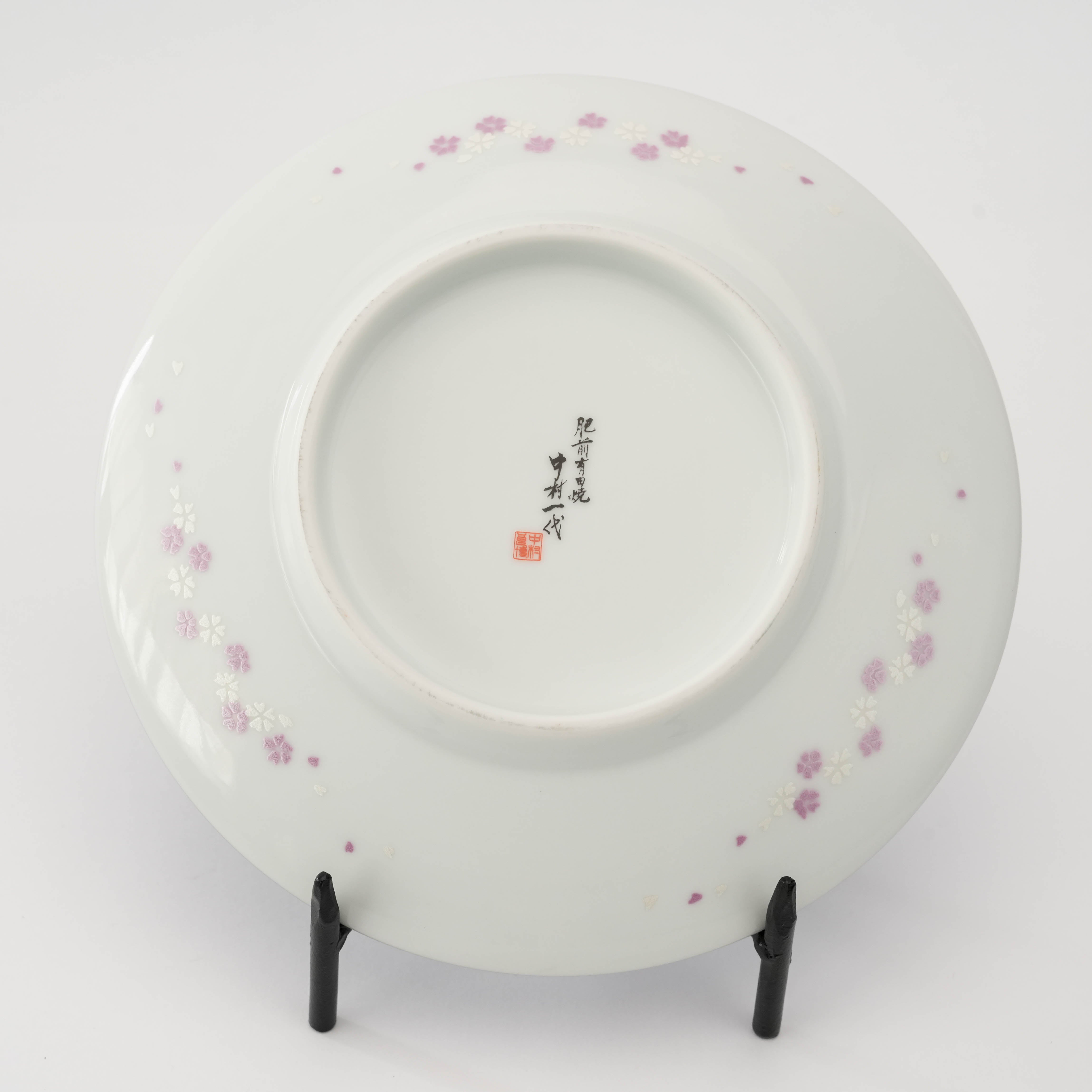 Underside of the Arita Yozakura Cherry Blossom saucer showing floral accents and artist Ichidai Nakamura’s signature in Japanese calligraphy.