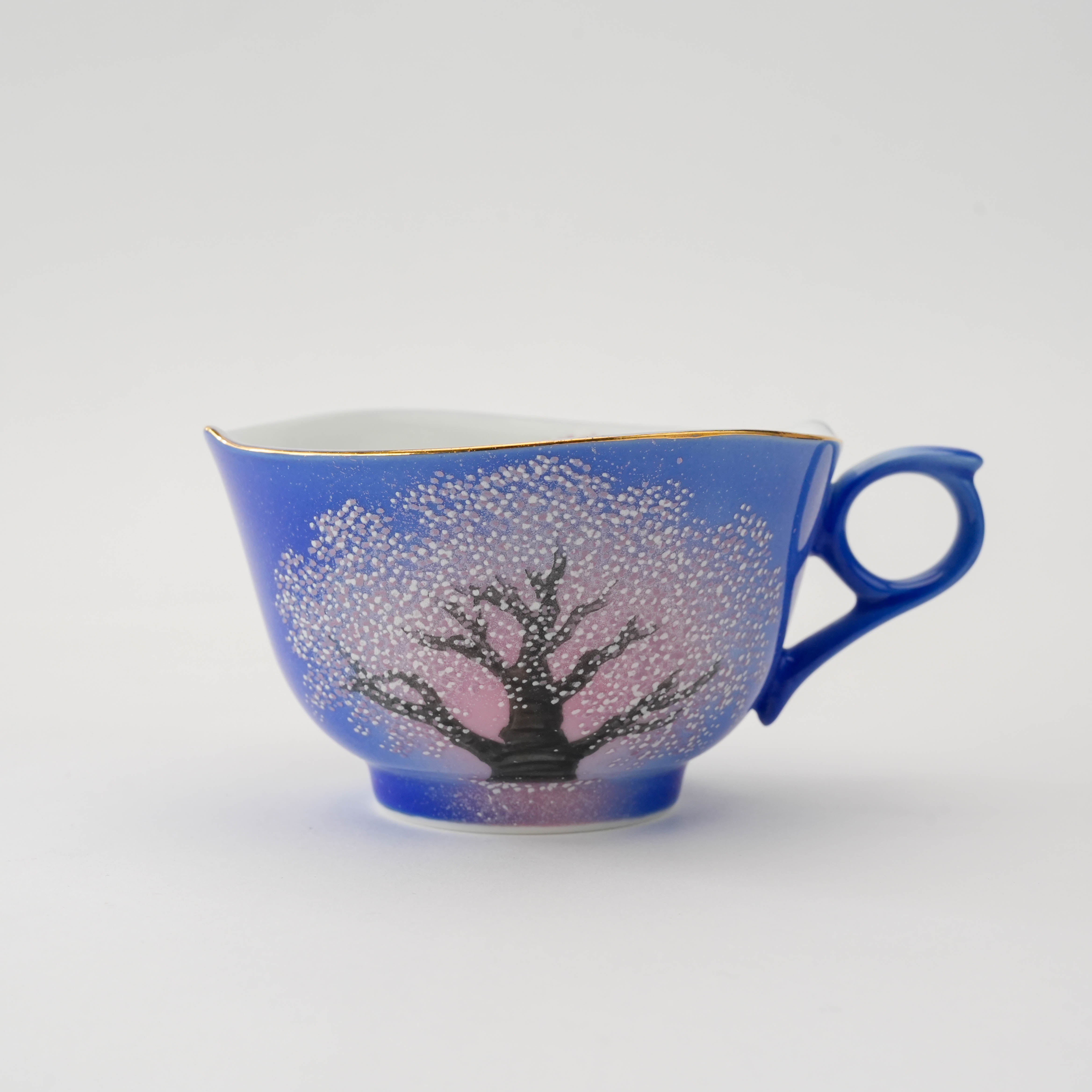 Side view of the Arita Yozakura Cherry Blossom tea cup with a vivid blue glaze and delicate hand-painted cherry blossom tree.