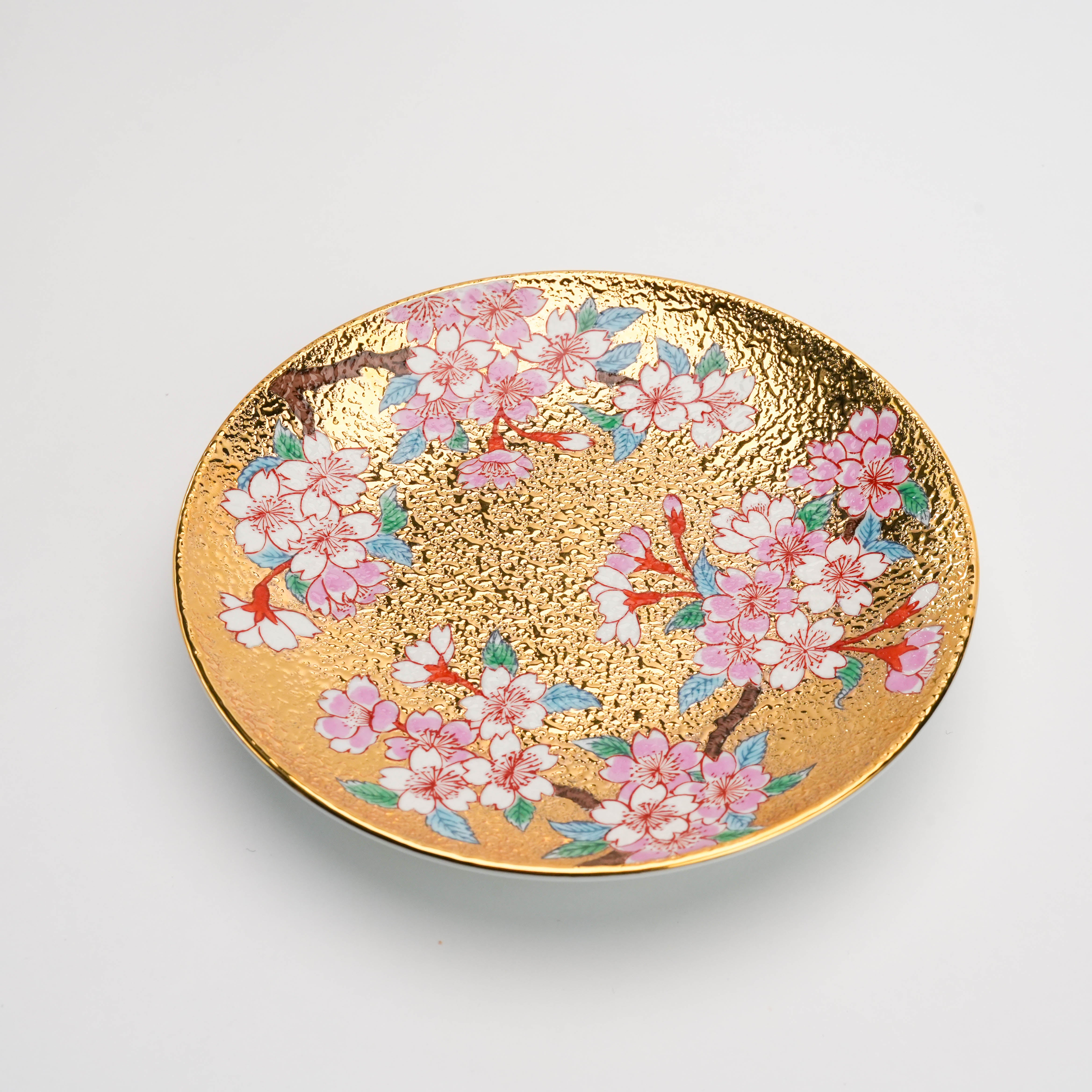 Close-up of the saucer from the Arita Ware Gold Sakura Cup & Saucer set. Features intricate hand-painted sakura on a textured gold background.