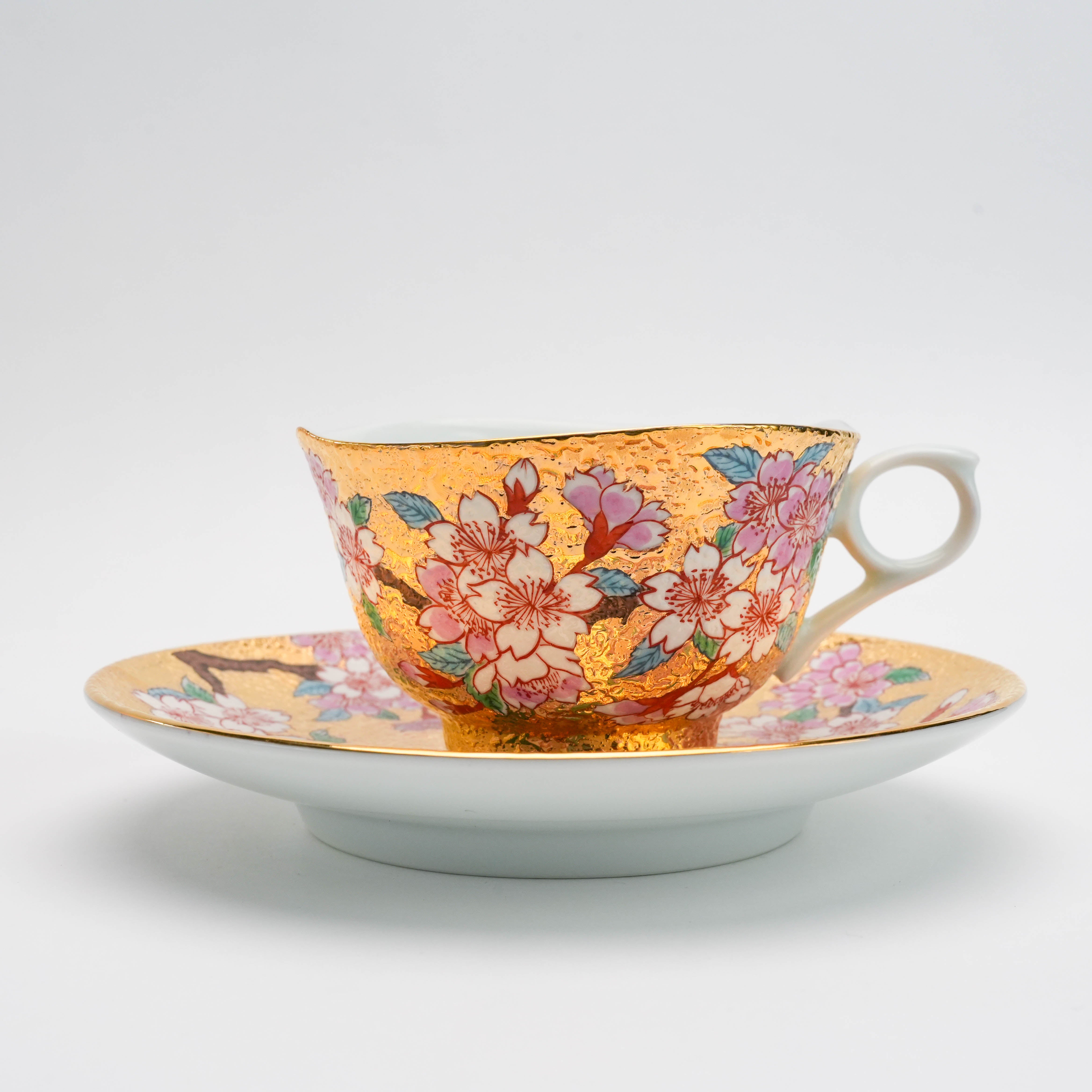 Side view of the Arita Ware Sakura Cup & Saucer by Tendou Eguchi. Features vivid sakura blossoms on a gold leaf background for elegant tea service.