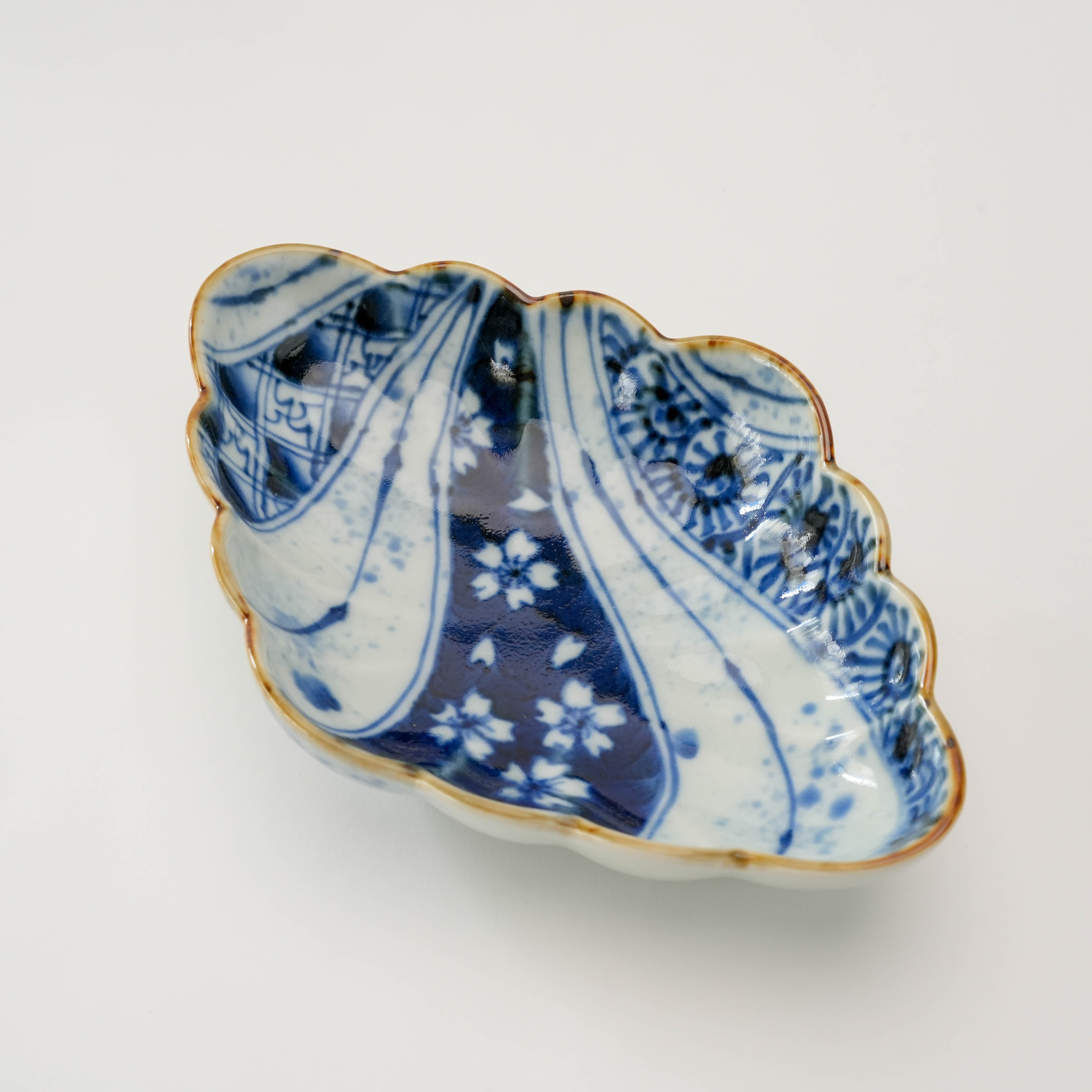 Angled view of Arita Ware Diamond Bowl with chrysanthemum design and curved edges, showcasing traditional Japanese craftsmanship.