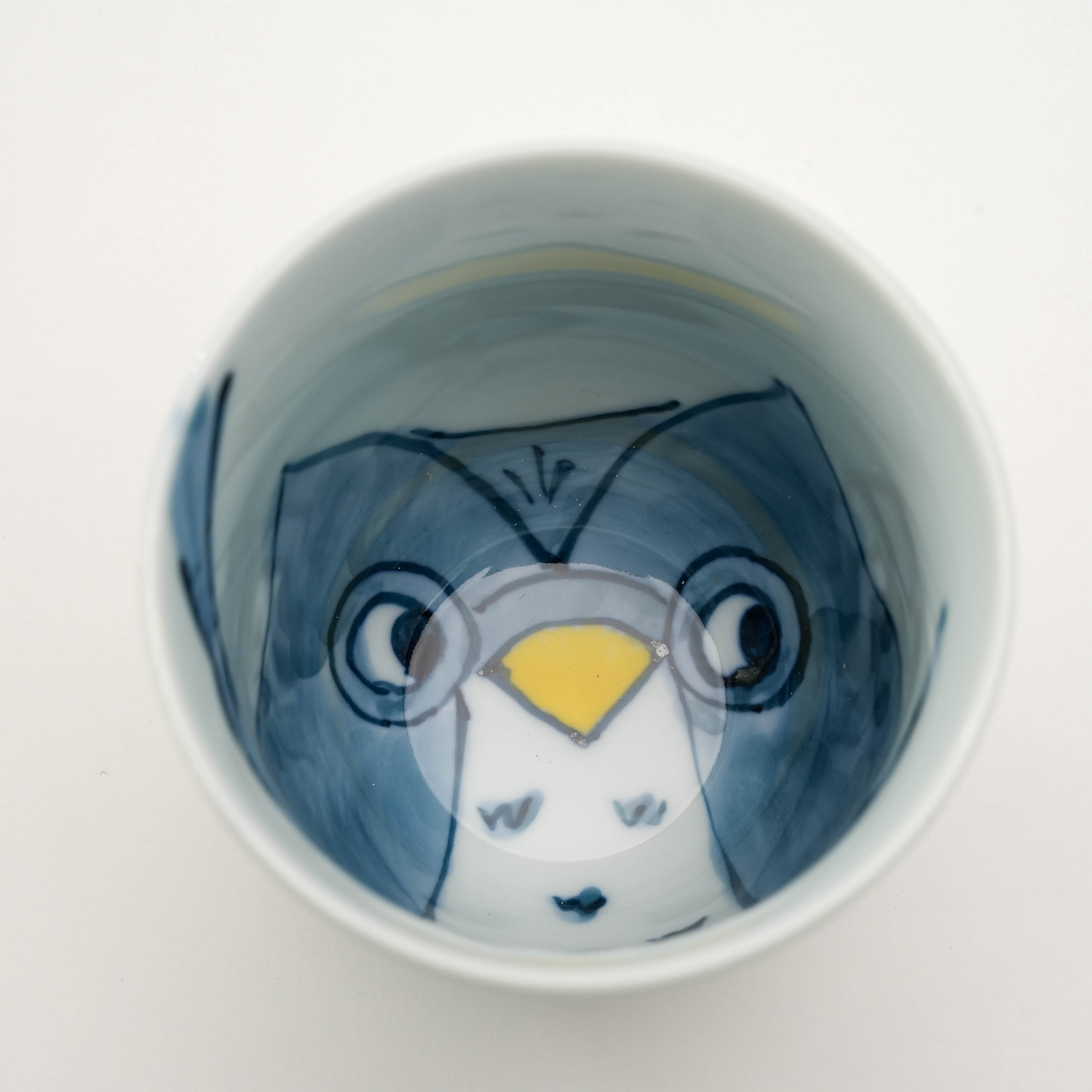 Close-up of blue owl illustration inside Arita Ware Teacup. Unique Japanese porcelain drinkware with whimsical design.