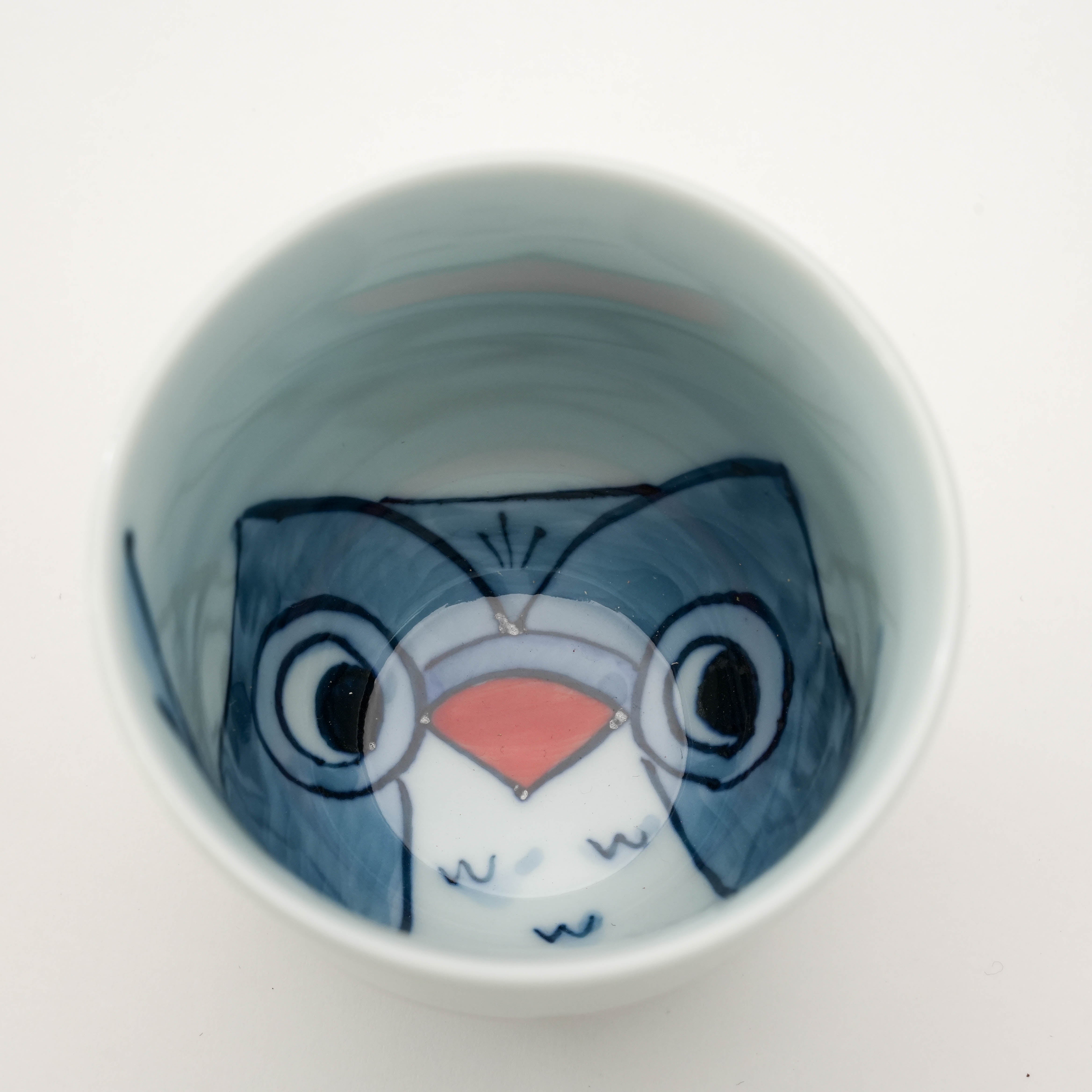 Close-up of red owl illustration inside Arita Ware Teacup. Stylish Japanese porcelain mug with hidden character detail.