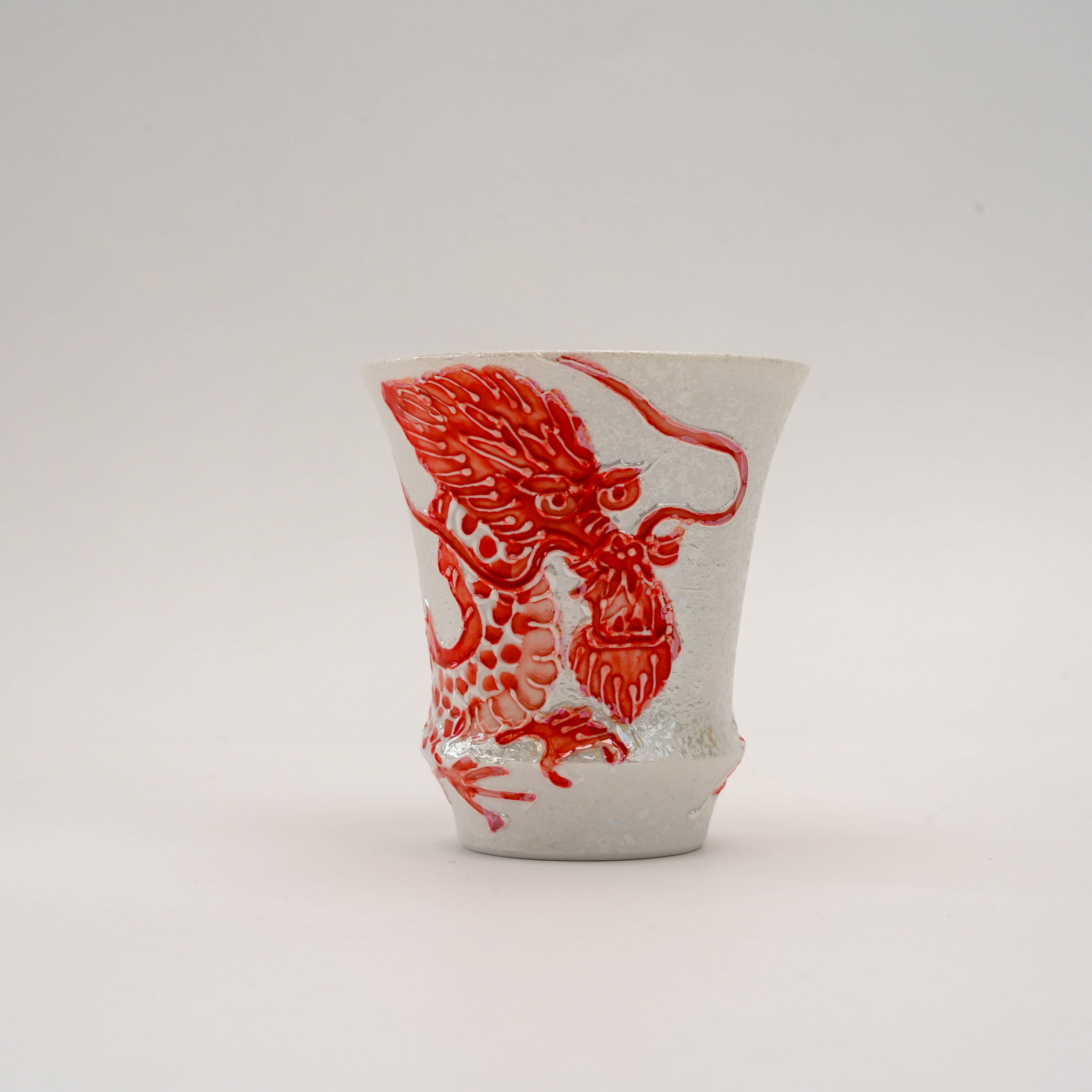 Close-up of the Fire Dragon Sake Glass showcasing the fierce red dragon head embossed on fine Arita porcelain with silver detailing.