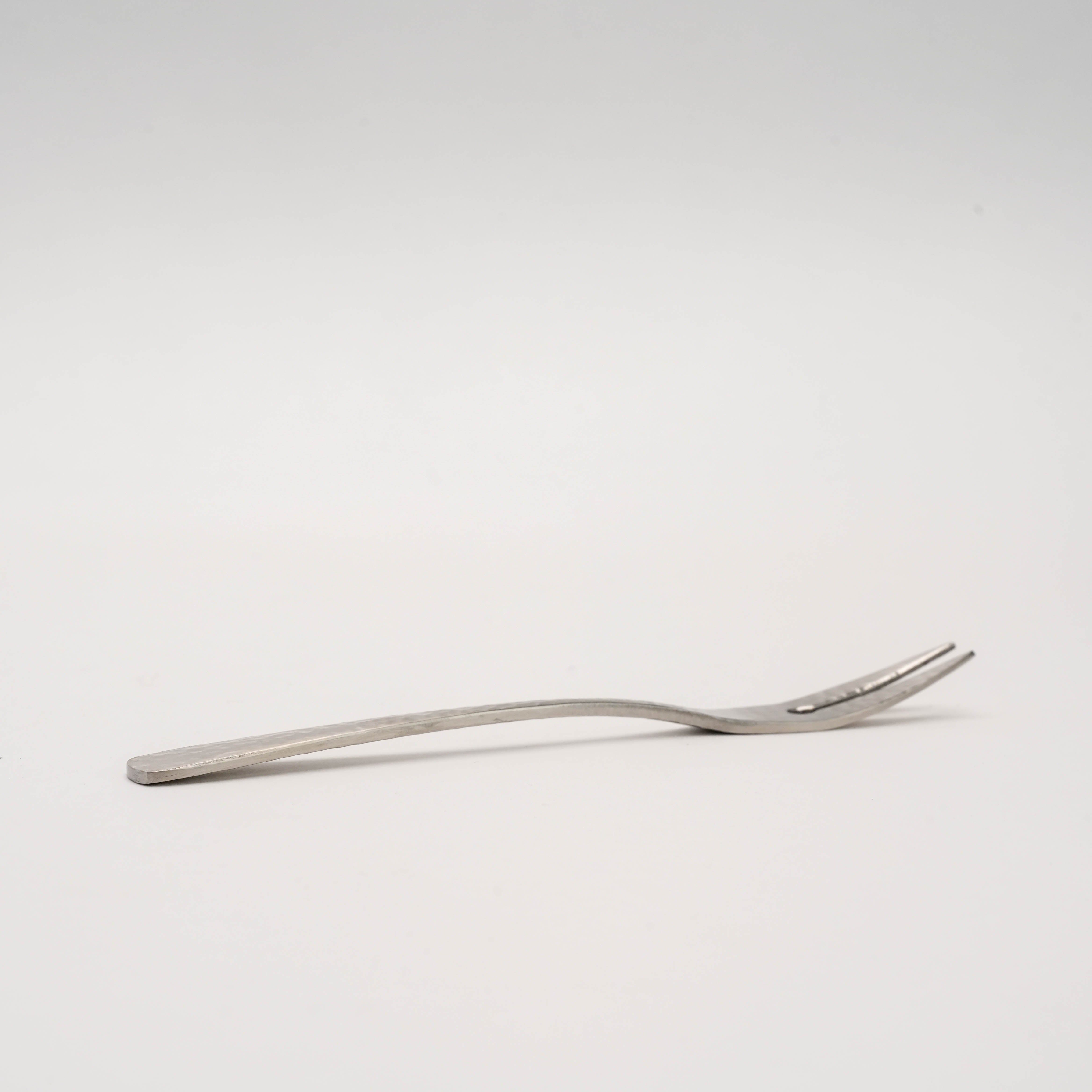 Side view of Nagomi Wafu Fork with curved handle and hammered finish, showcasing Japanese craftsmanship in premium cocktail utensils.