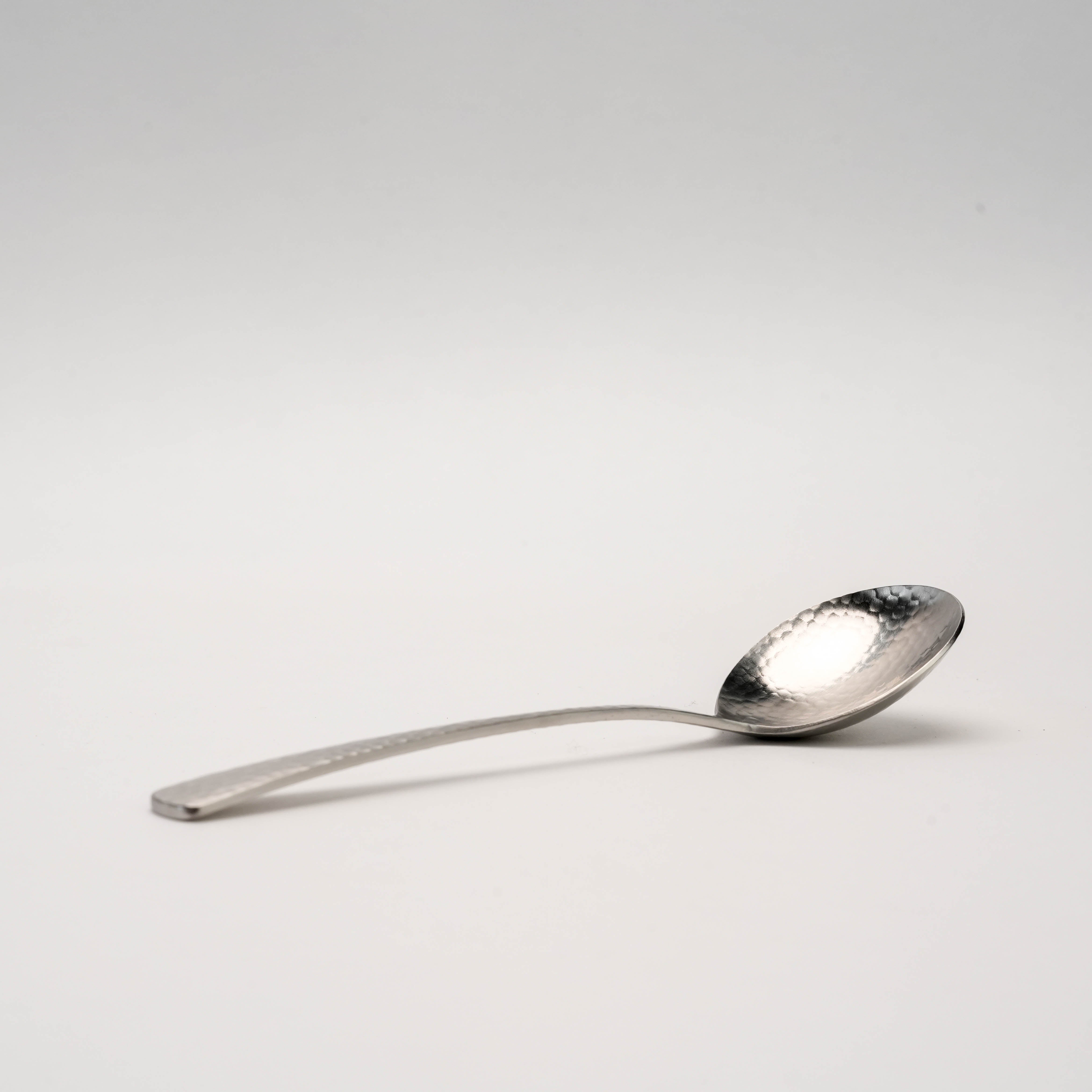Side view of the Nagomi Wafu Hammered Soup Spoon highlighting its curved handle and artisanal hammered detailing, perfect for soup and broths.