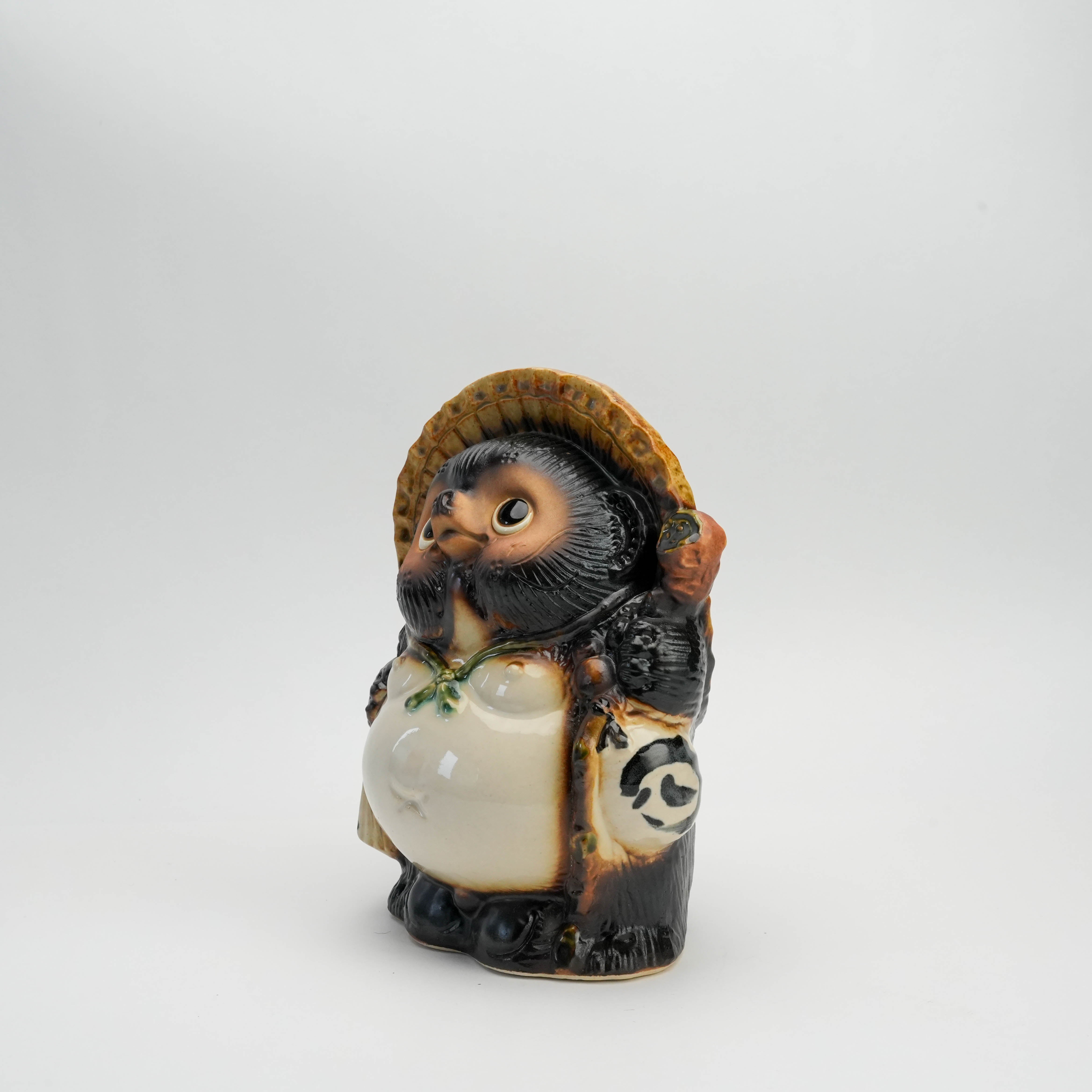 Angled right view of Shigaraki Ware Lucky Tanuki Raccoon Ornament holding a scroll and sake bottle, ideal for home decor or gifting.