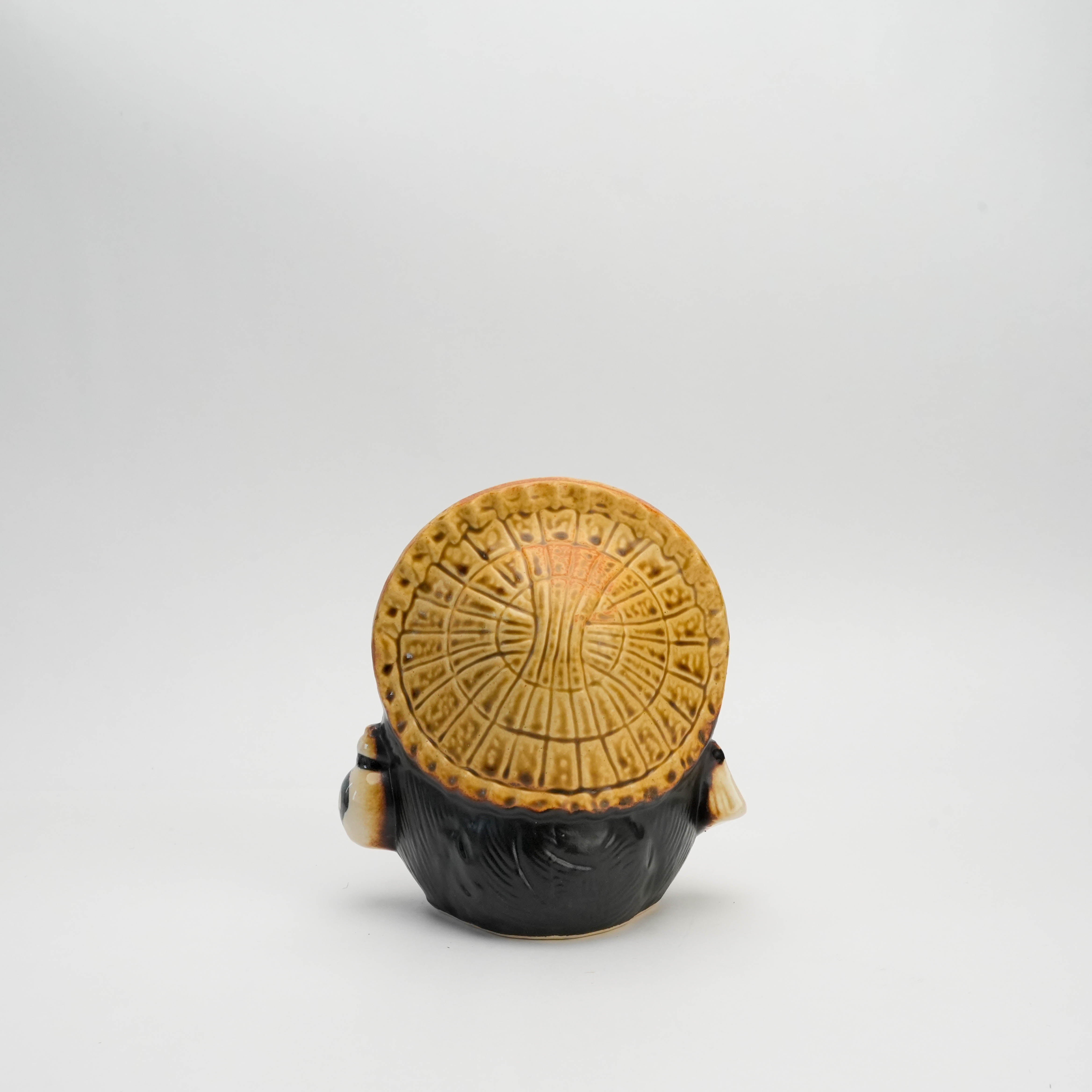 Back view of Shigaraki Tanuki ornament showing textured straw hat, part of traditional Japanese lucky raccoon dog decor.