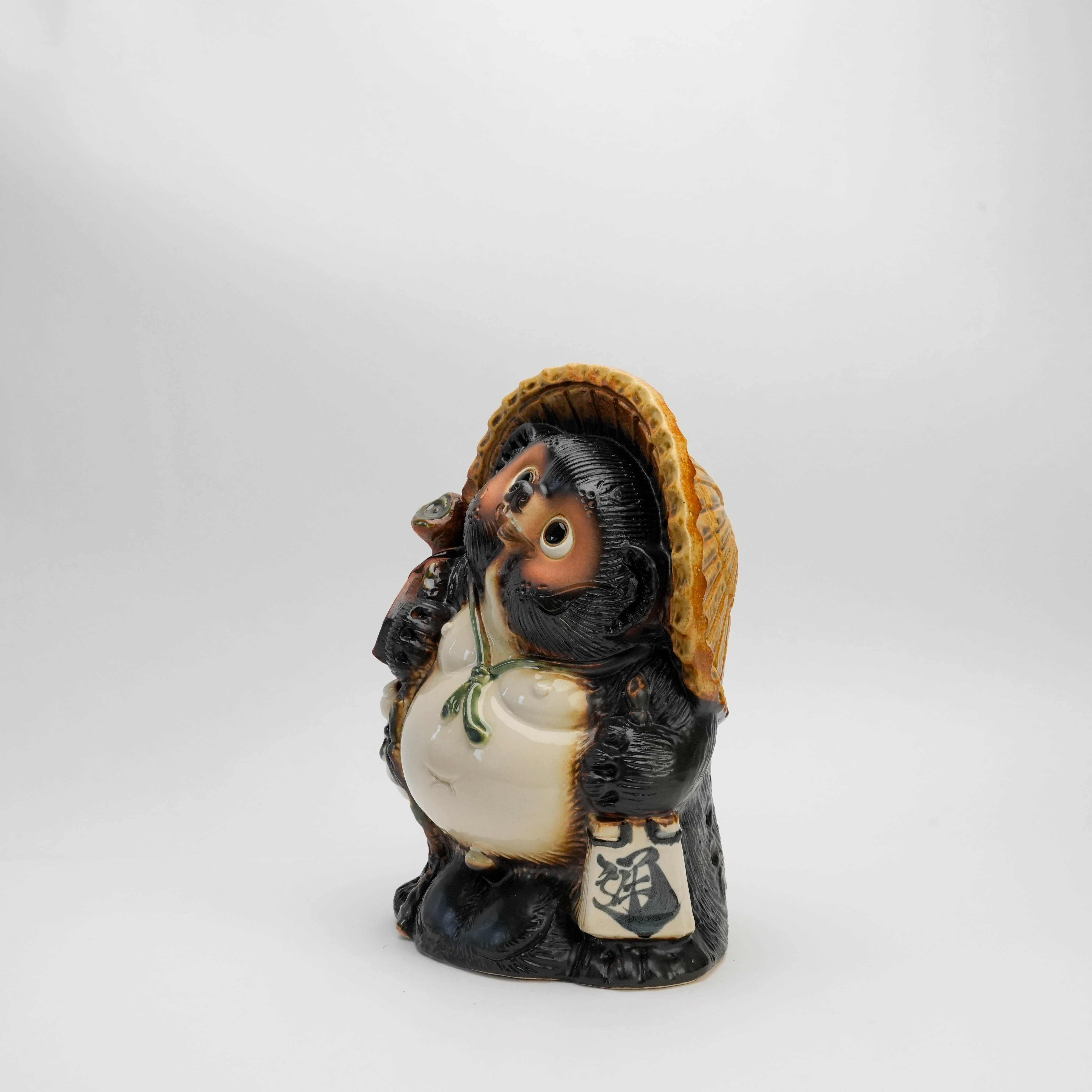Angled view of Shigaraki Ware Lucky Tanuki figurine holding scroll and sake flask, handcrafted for good fortune and decorative charm.