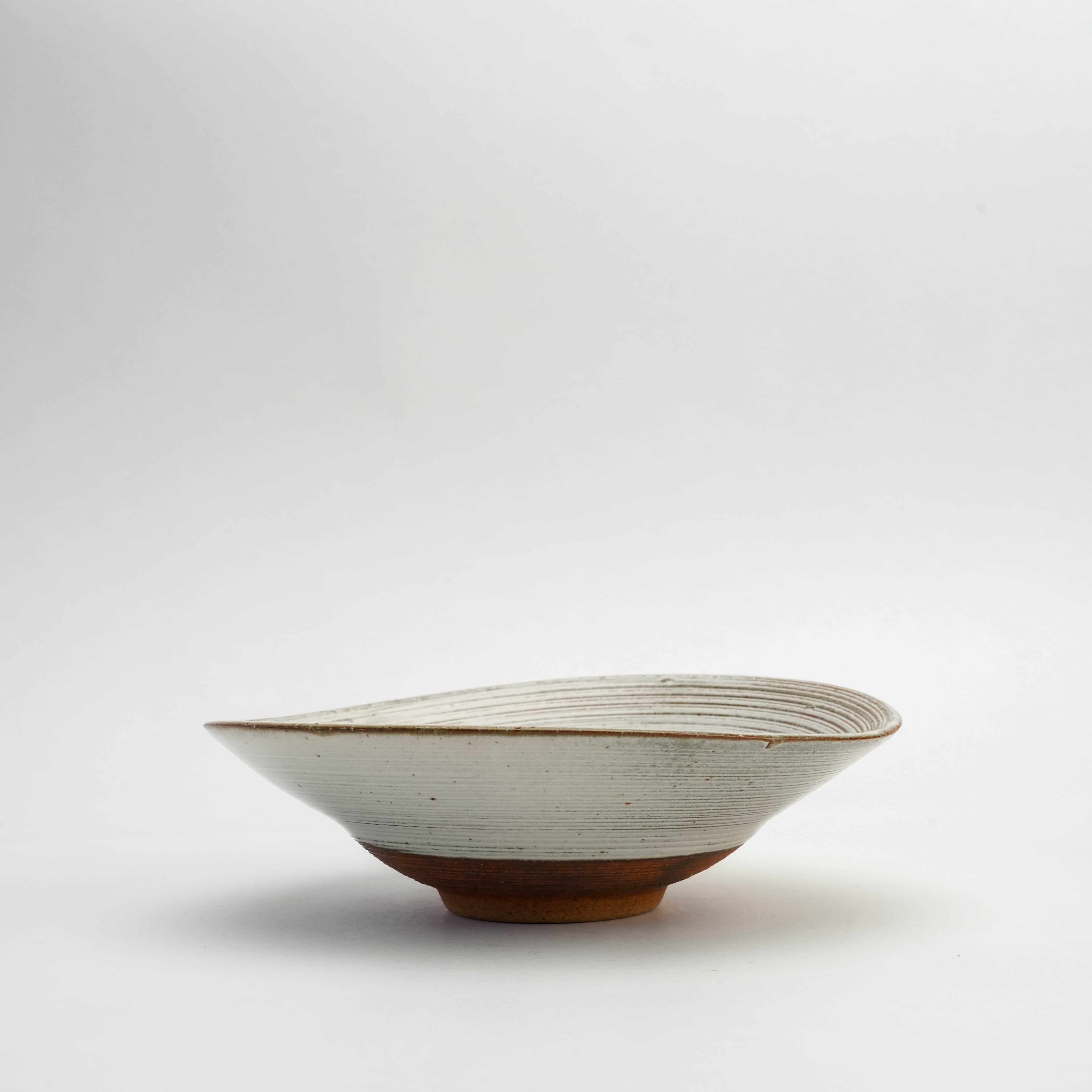 Side profile of Japanese Mino Ware Kushime Bowl featuring a unique asymmetrical twist and earthy ceramic base for artisanal presentation.