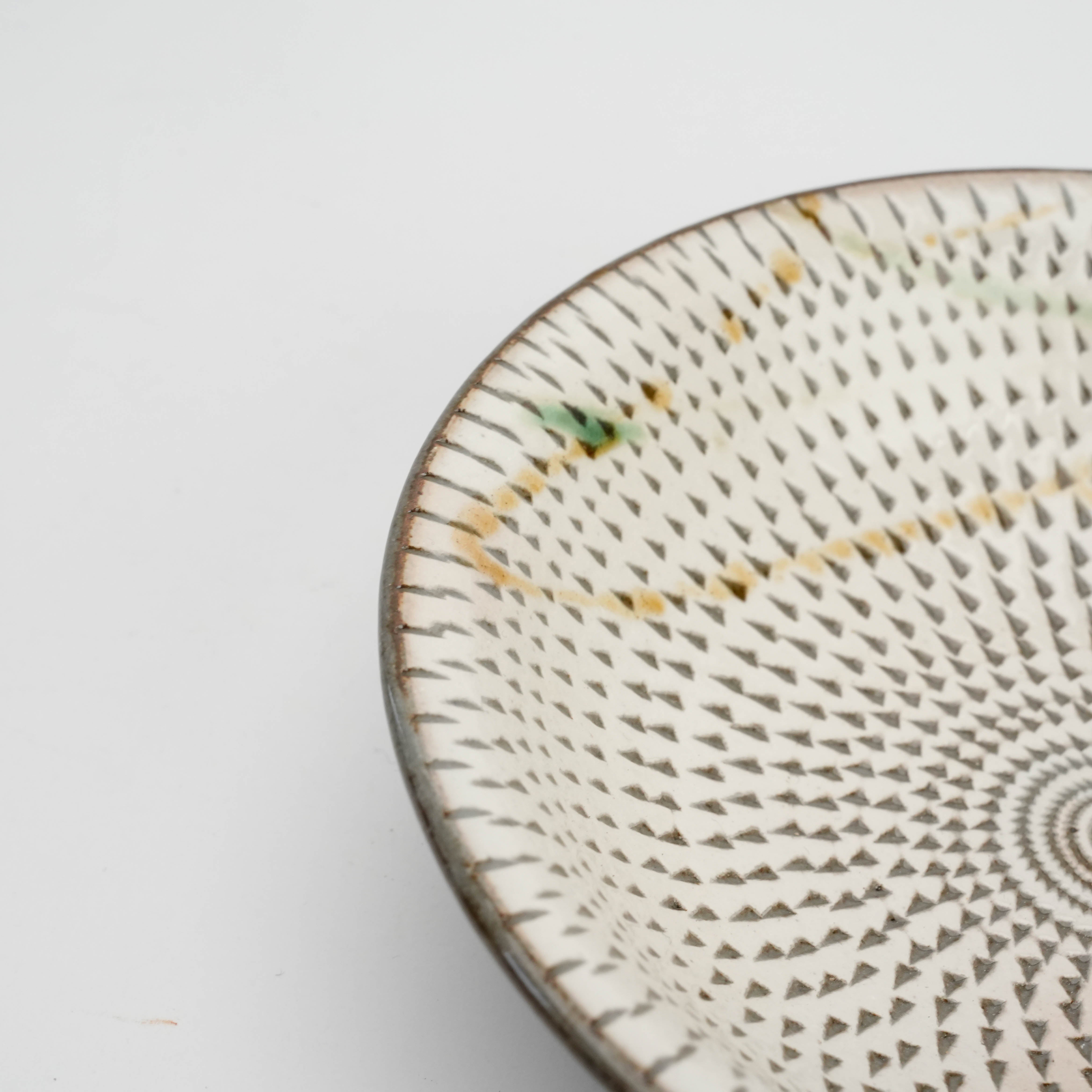 Close-up of Tobikanna-style carving on Mino Ware Japanese bowl, highlighting intricate texture and subtle green and amber glaze accents.