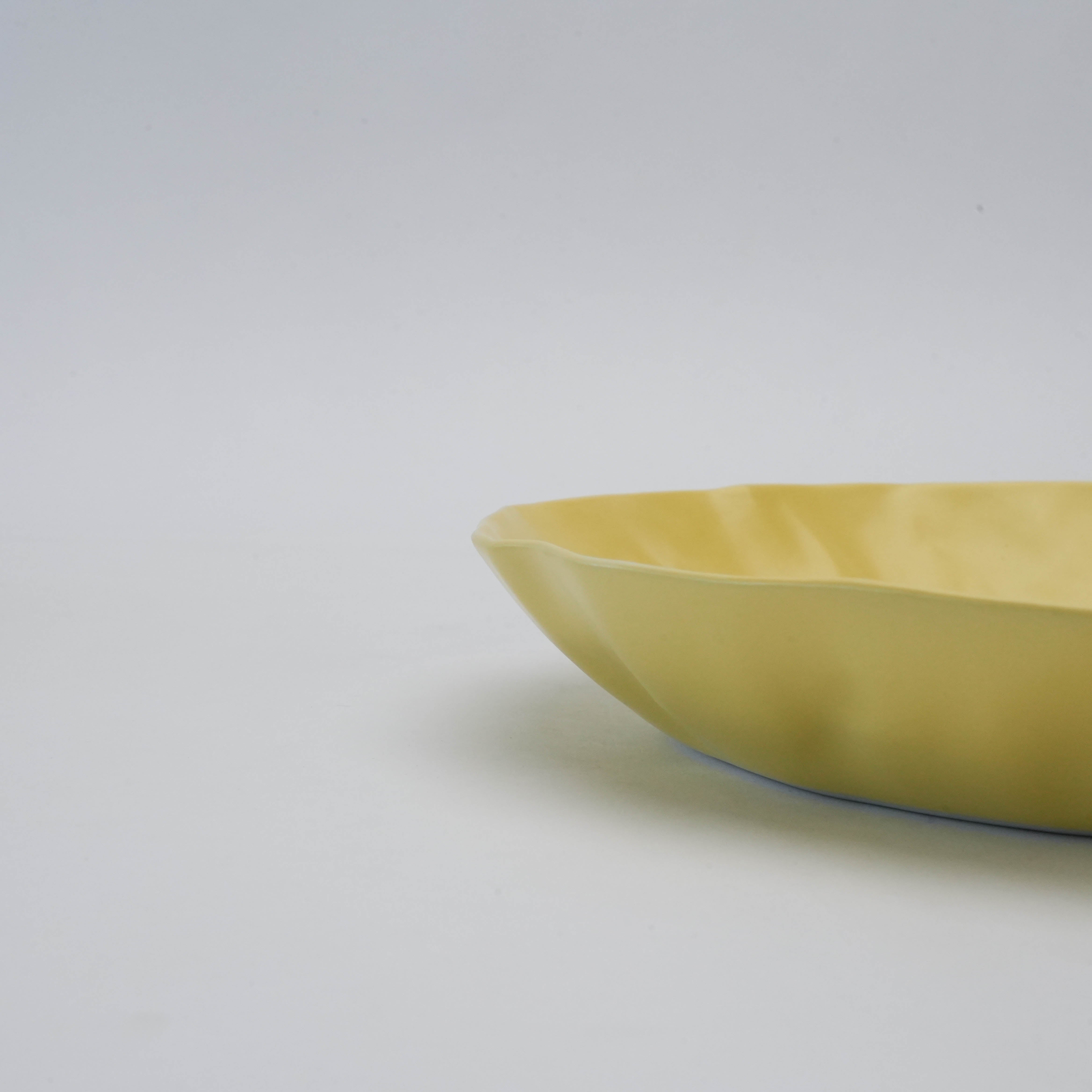 Angled side view of yellow Hasami Ware Pasta Dish emphasizing its handcrafted papyrus-inspired rim and minimalist form.