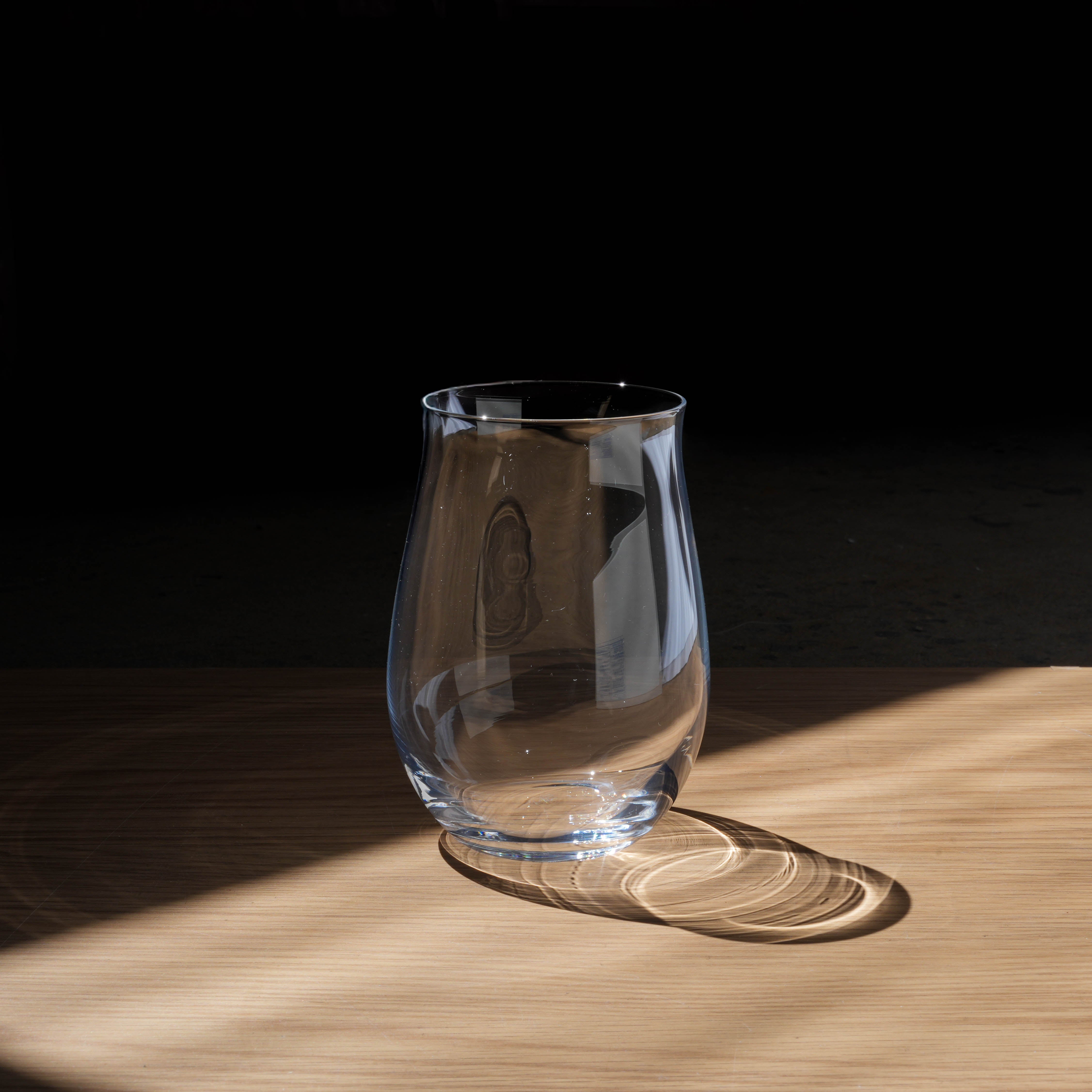 Toyo-Sasaki Wine Glass Tumbler from HS Series, made in Japan, shown on wooden surface with natural light reflection. Ideal for wine lovers.