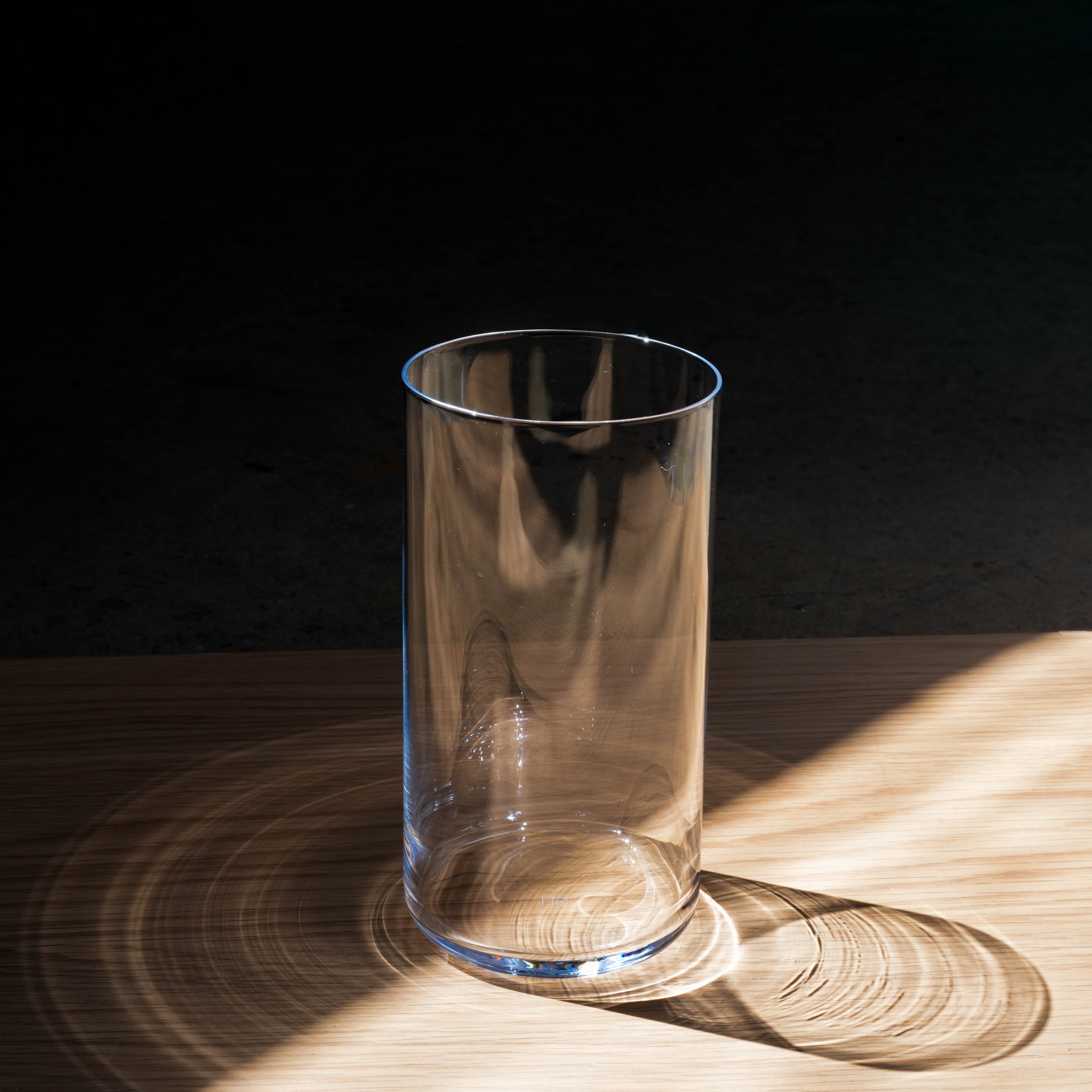 Toyo-Sasaki Tall Tumbler - HS Glassware with a sleek, cylindrical design, shown on a wooden surface with natural light reflections.