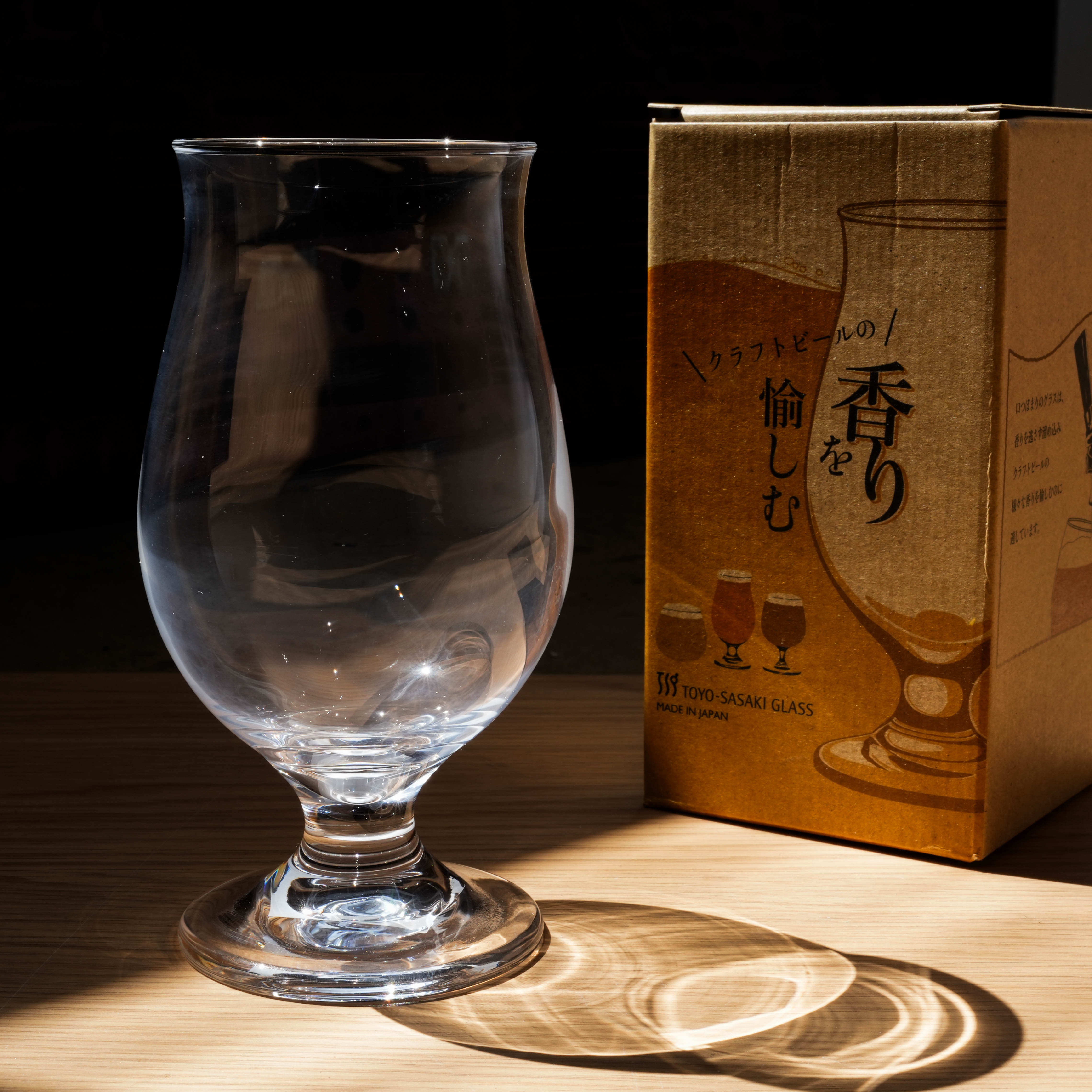 Toyo-Sasaki Tulip Beer Glass with box in warm lighting, emphasizing its design for craft beer aroma enhancement and presentation.