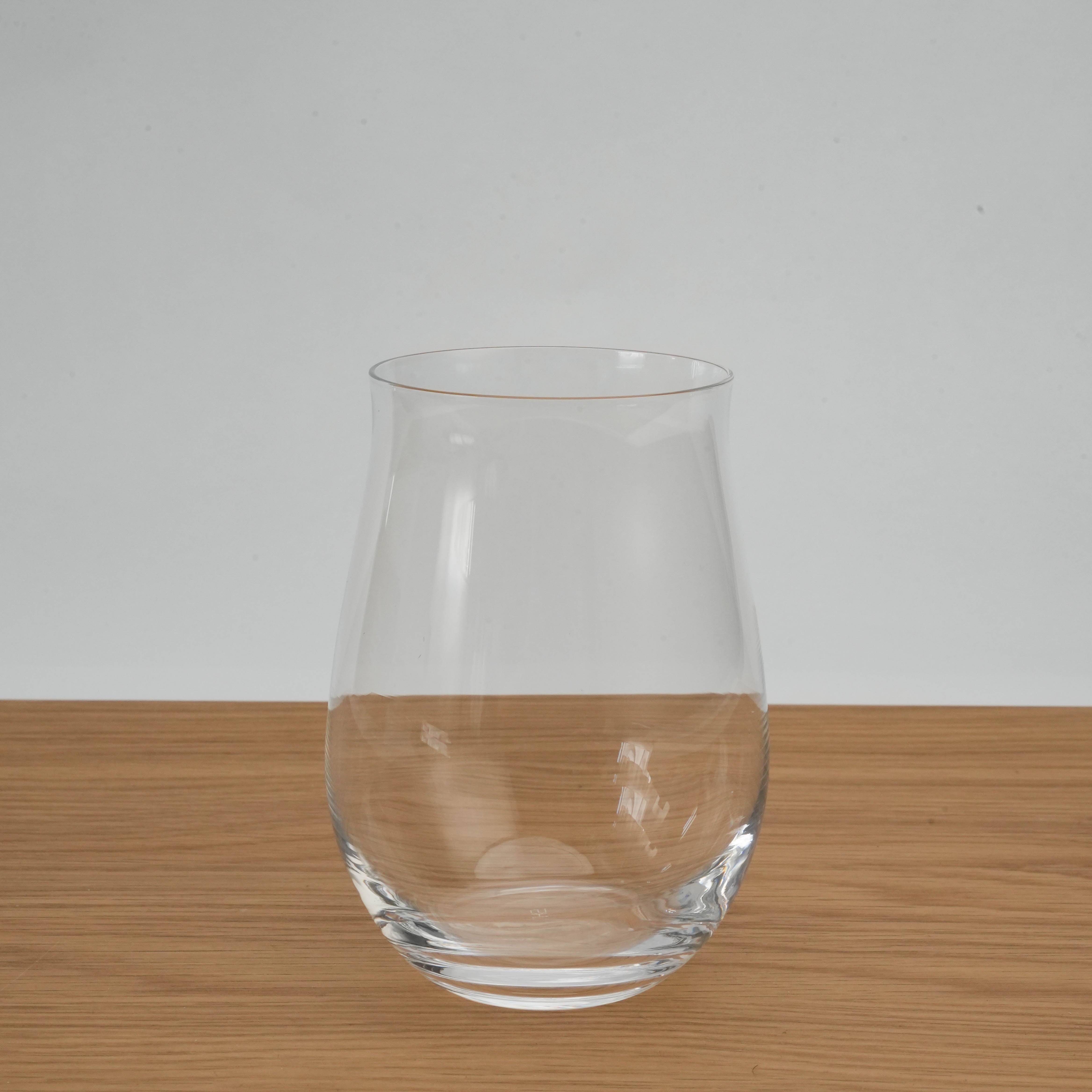 Clear Toyo-Sasaki HS Fino Wine Glass Tumbler on wooden table, showcasing its curved silhouette and minimalist Japanese craftsmanship.
