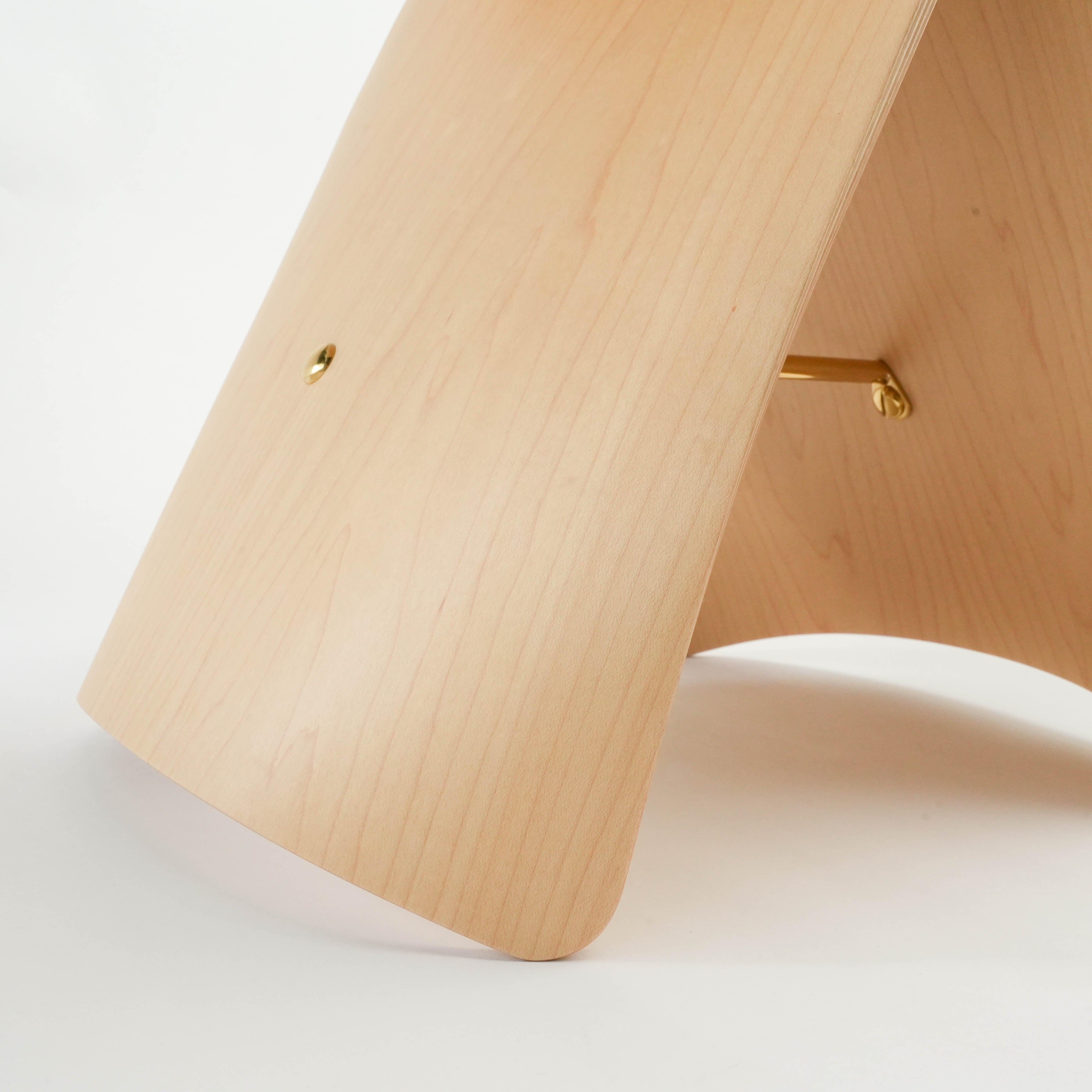 Close-up of light wood Butterfly Stool leg, showing fine grain texture and brass screw detail for premium craftsmanship.