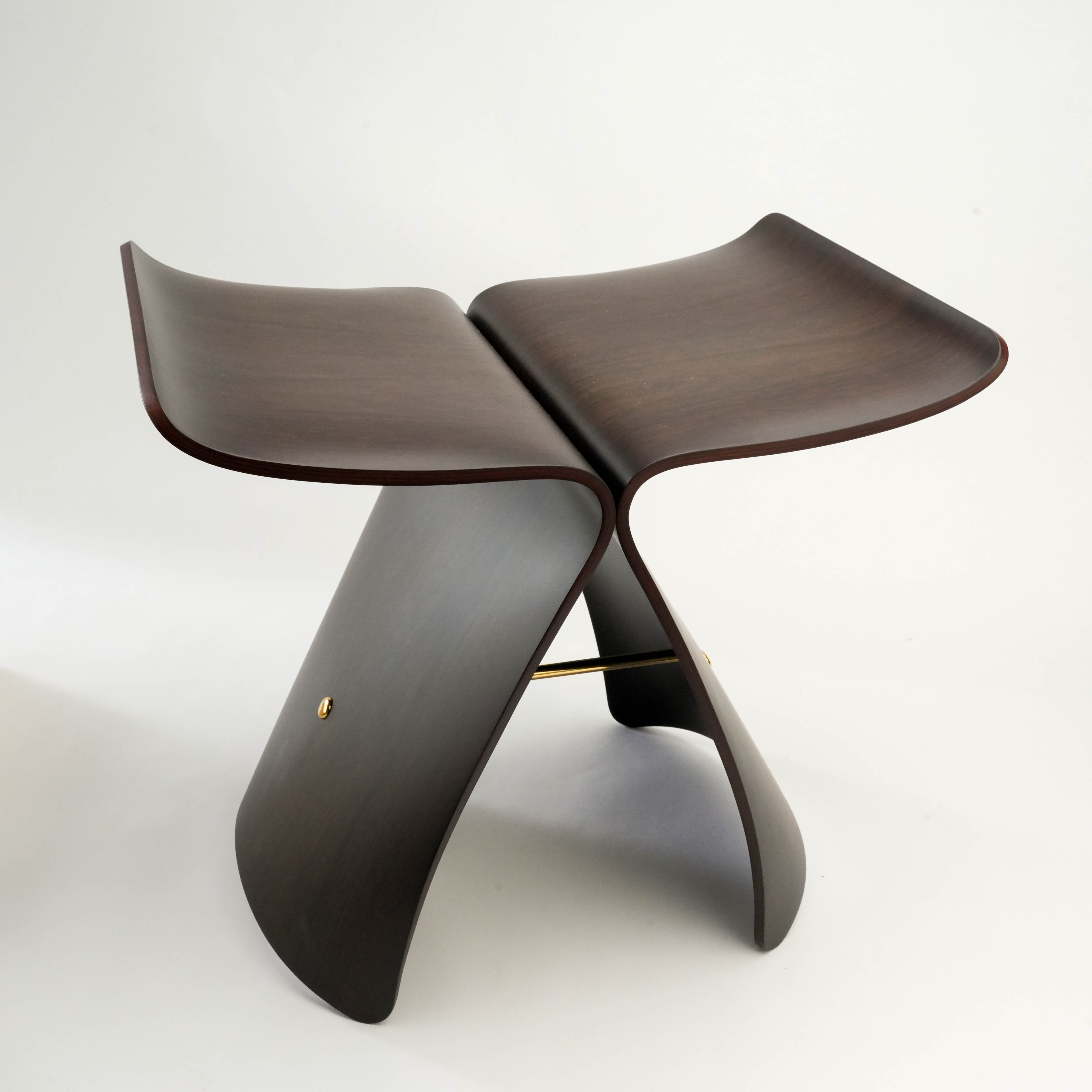 Sori Yanagi Butterfly Stool in dark molded plywood finish, a Japanese design icon with smooth contours and brass crossbar.