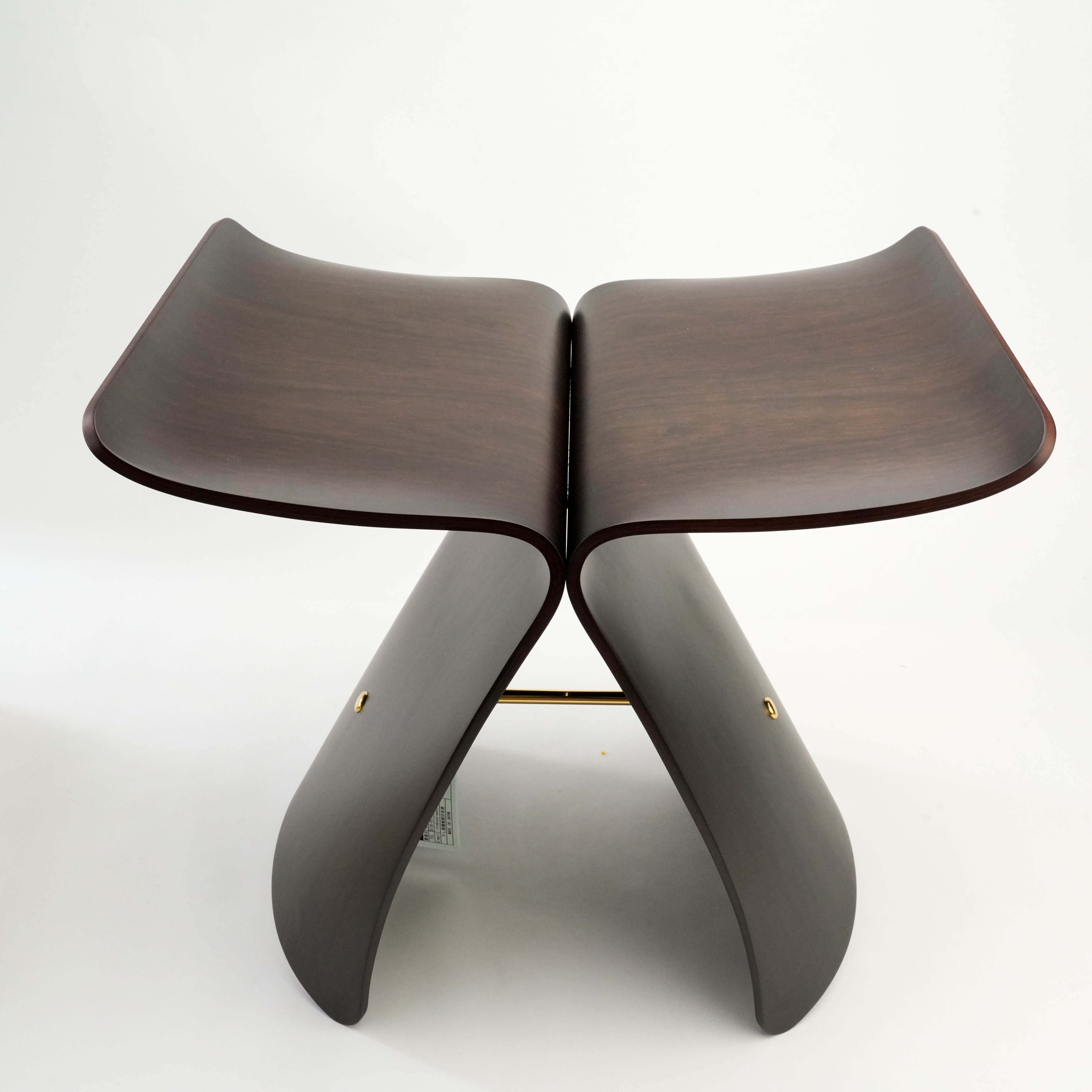 Front view of dark wood Butterfly Stool by Sori Yanagi, featuring sculptural molded plywood and polished brass accents.