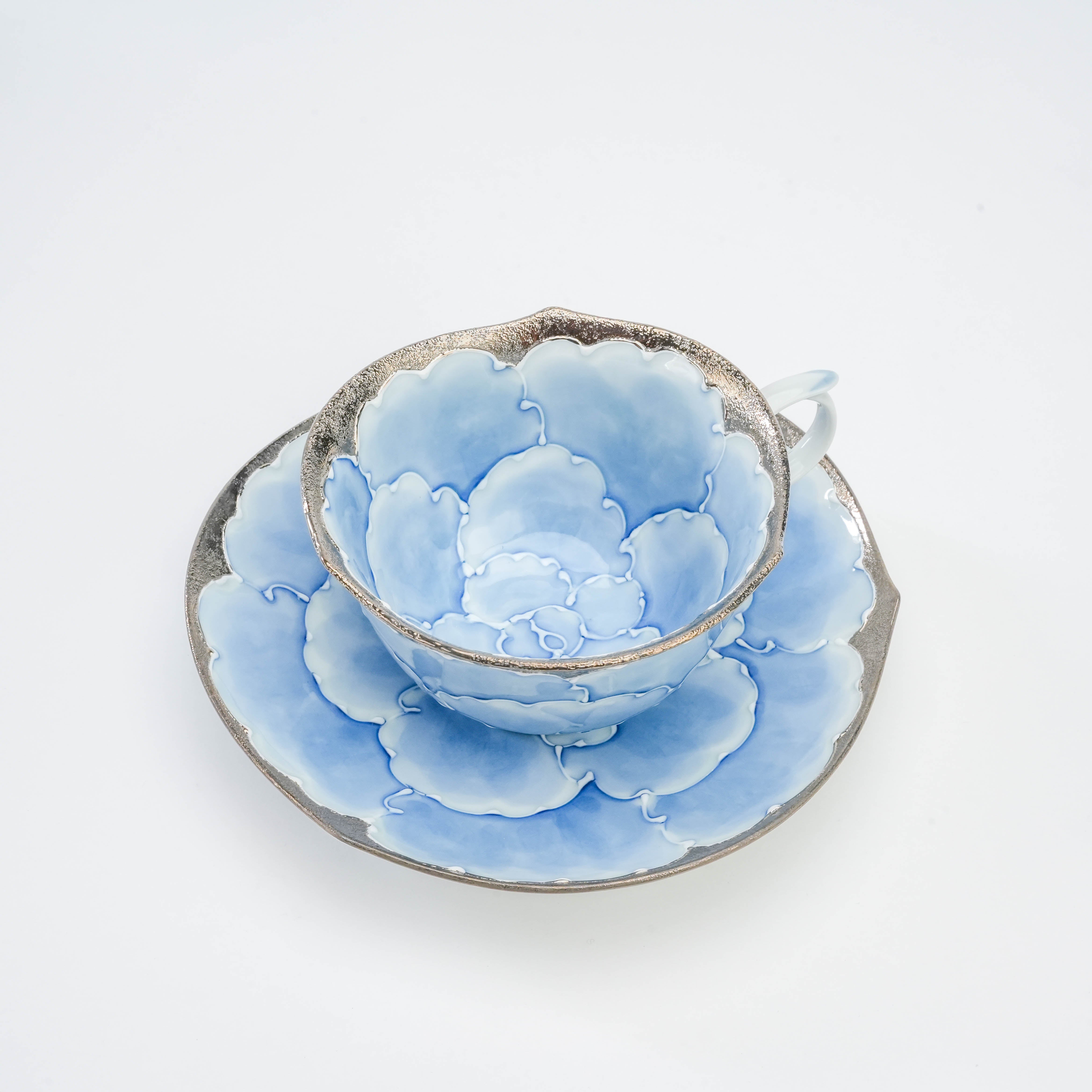 Top view of Bunzan Kiln Arita porcelain cup and saucer set with intricate blue peony petals and shimmering silver trim, perfect for elegant dining.