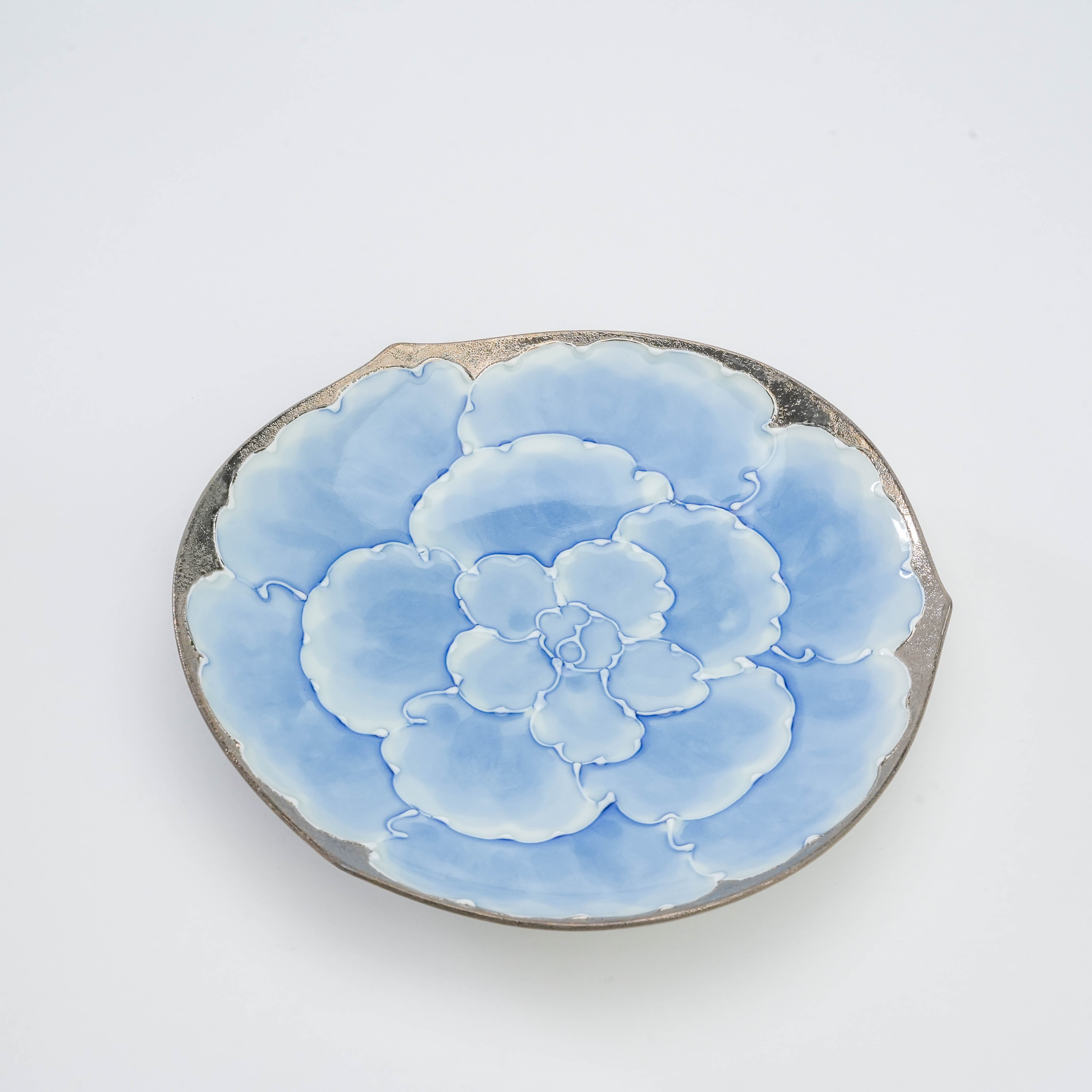 Close-up of the saucer from the Bunzan Kiln Peony Porcelain Set, showcasing detailed blue floral artwork and silver-edged craftsmanship.