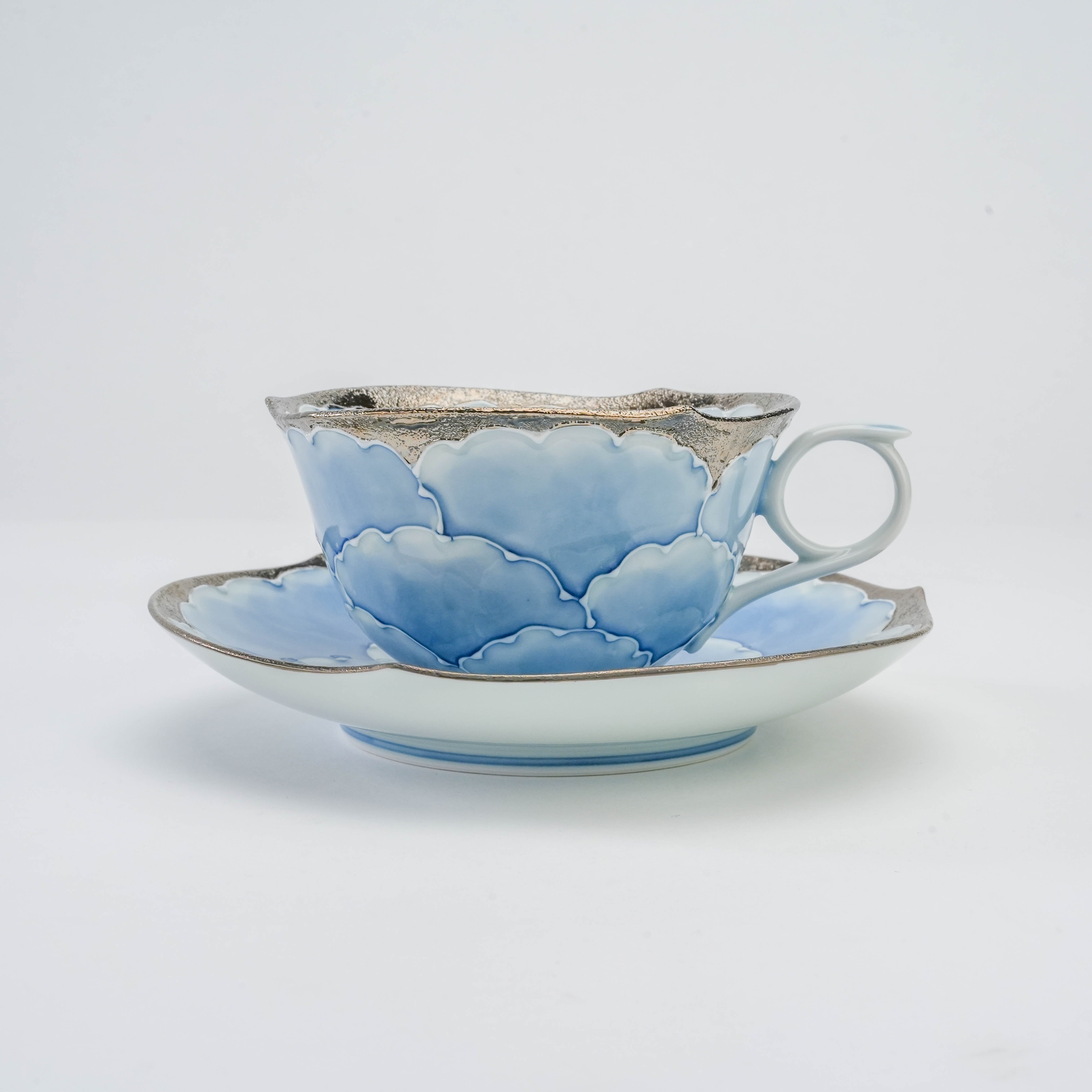 Side profile of the Bunzan Kiln Arita porcelain cup and saucer with blue peony motif and silver accents, ideal for luxury tea settings.