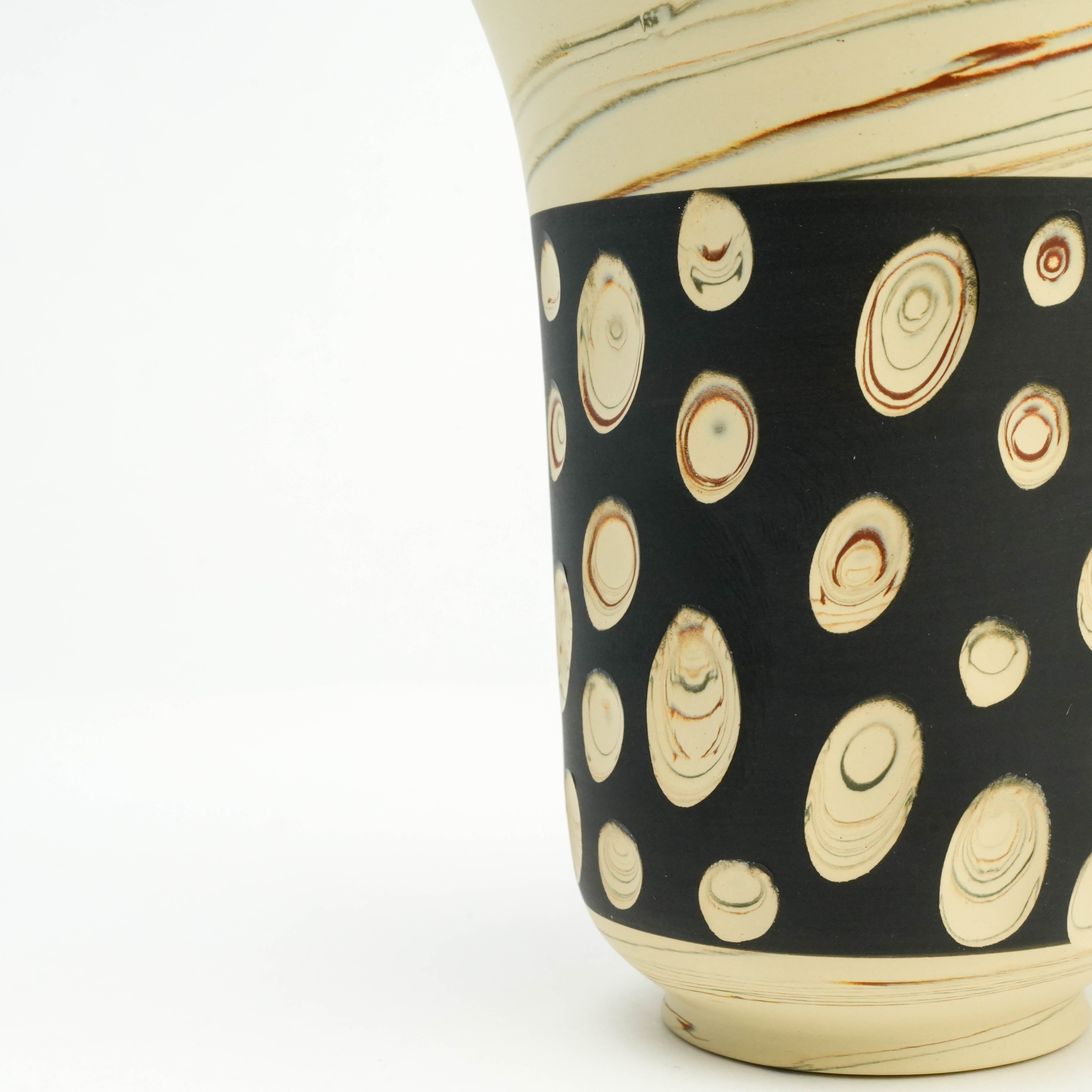Close-up of Tokoname Ware tumbler showing intricate nerikomi swirl patterns on black background, crafted by Kenji Touen.