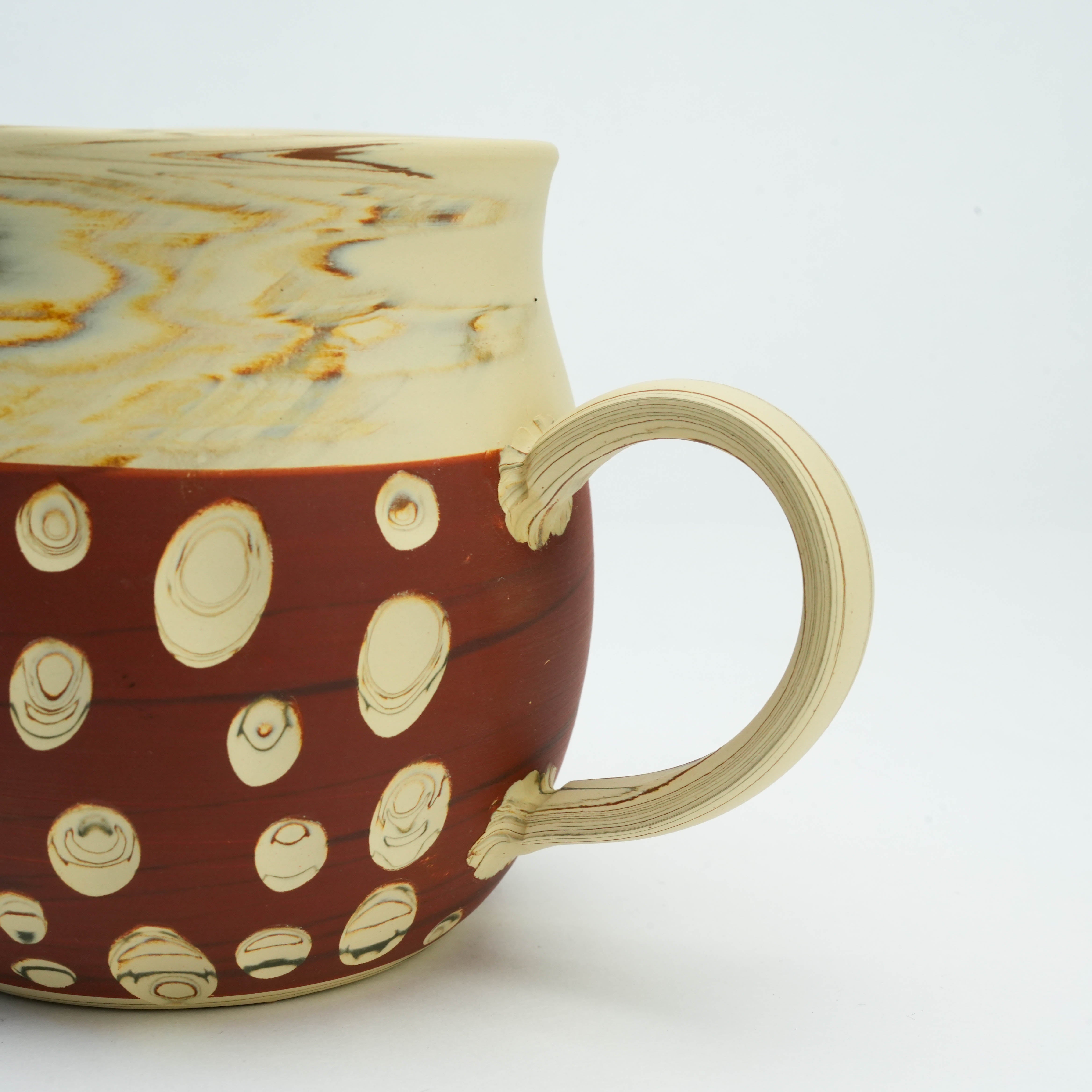 Detail of Tokoname Ware Polka Dot Mug handle and red base with carved dot pattern, emphasizing craftsmanship by Kenji Touen.