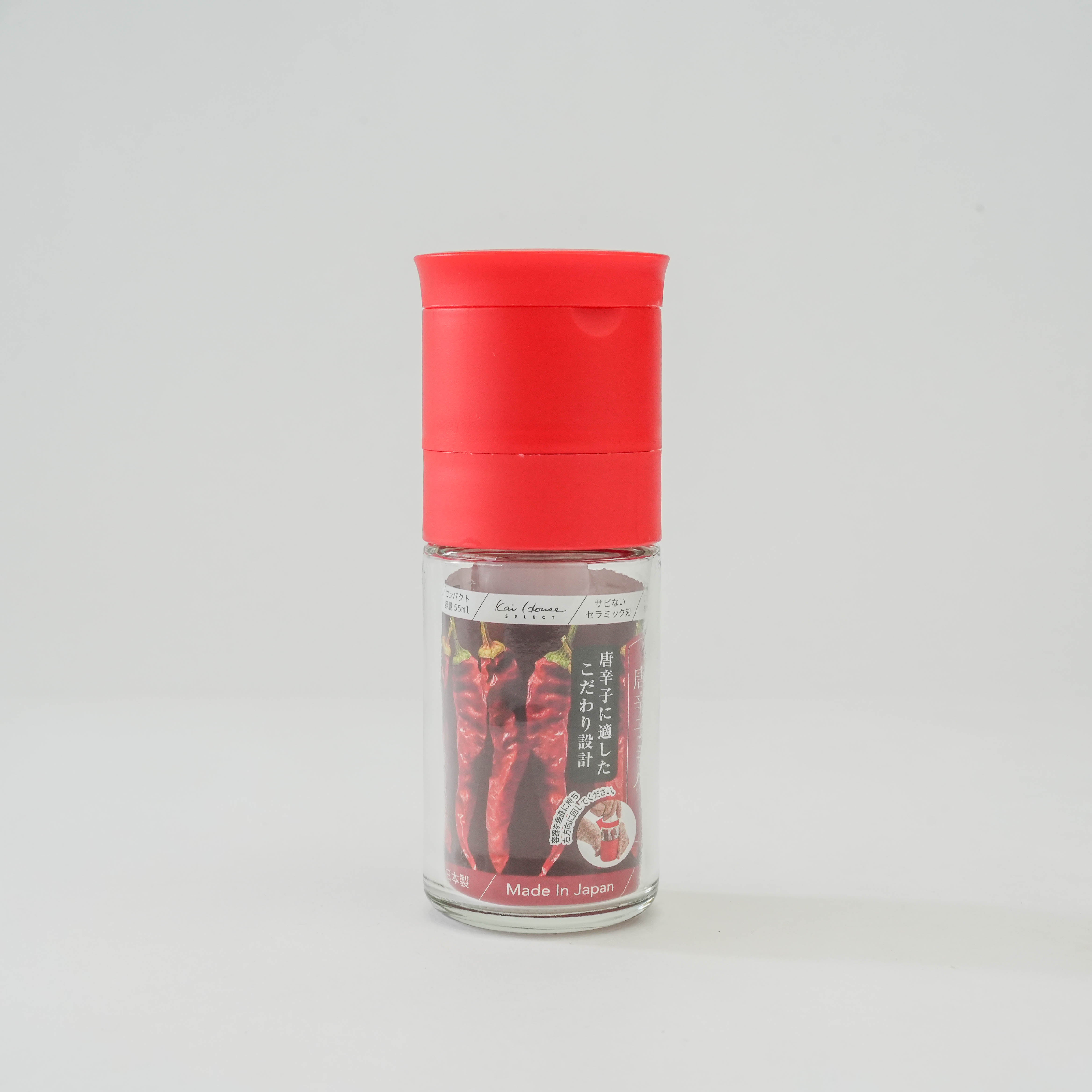 Kai Home Pepper Mill - Ceramic Grinder in bold red with clear body showing dried red peppers, ideal for stylish spice grinding in modern kitchens.