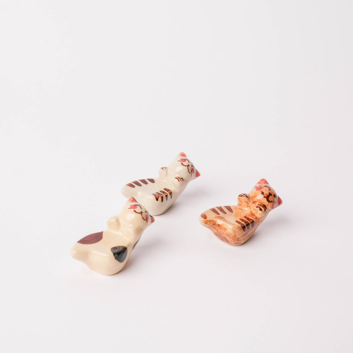 White porcelain Hasami Ware three friendly cat chopstick rest with hand-painted red and black details, small size for dining accessories