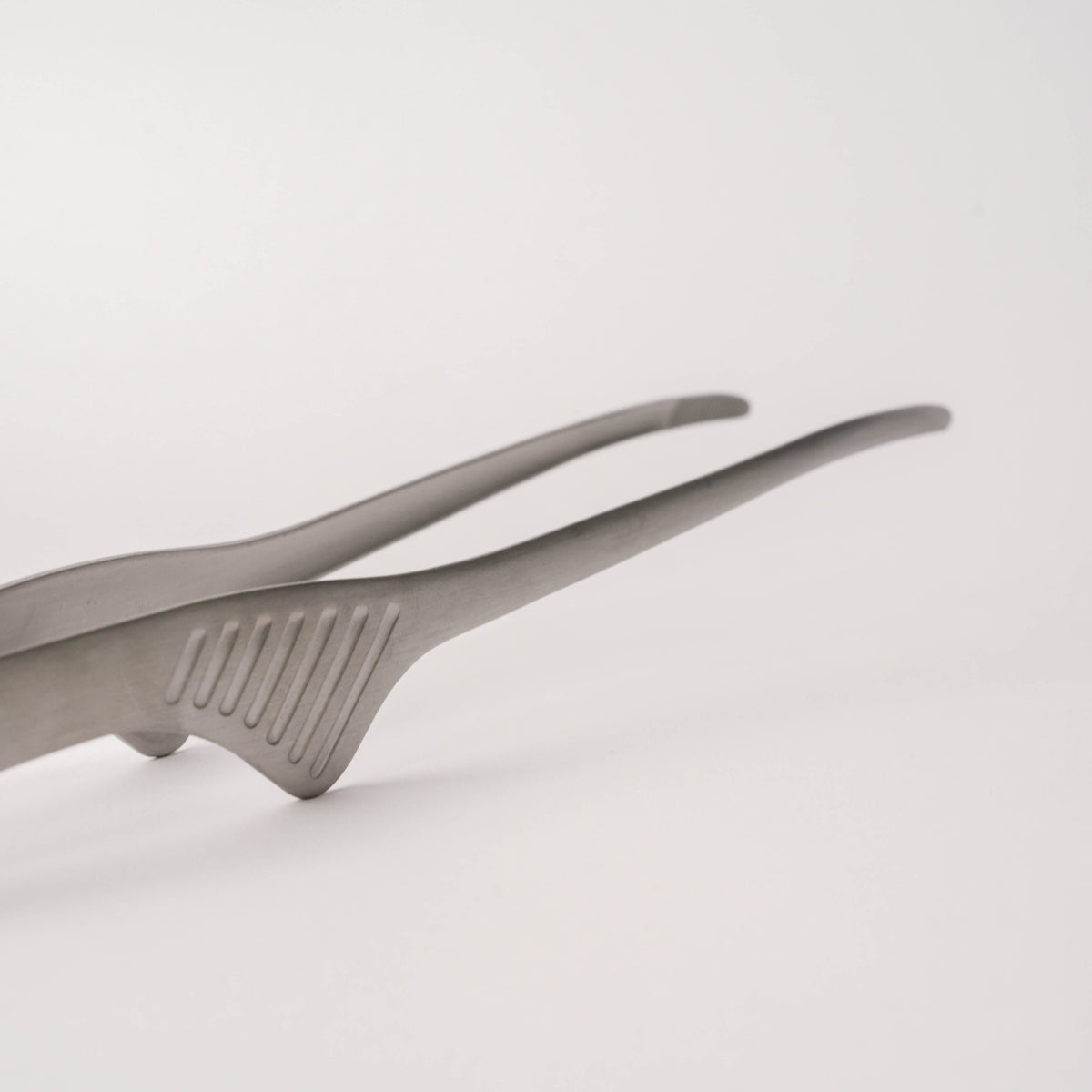 Close-up of stainless steel tongs with textured grip, showcasing durable and sleek design for kitchen use, SKU: 2052551