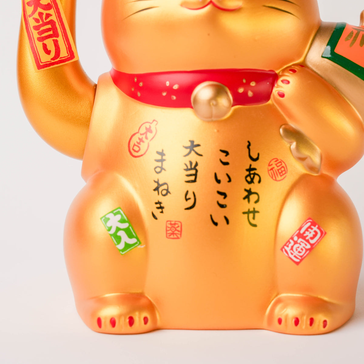 Front view of the gold Lucky Cat showing its waving paw, decorative Japanese characters, and traditional symbols