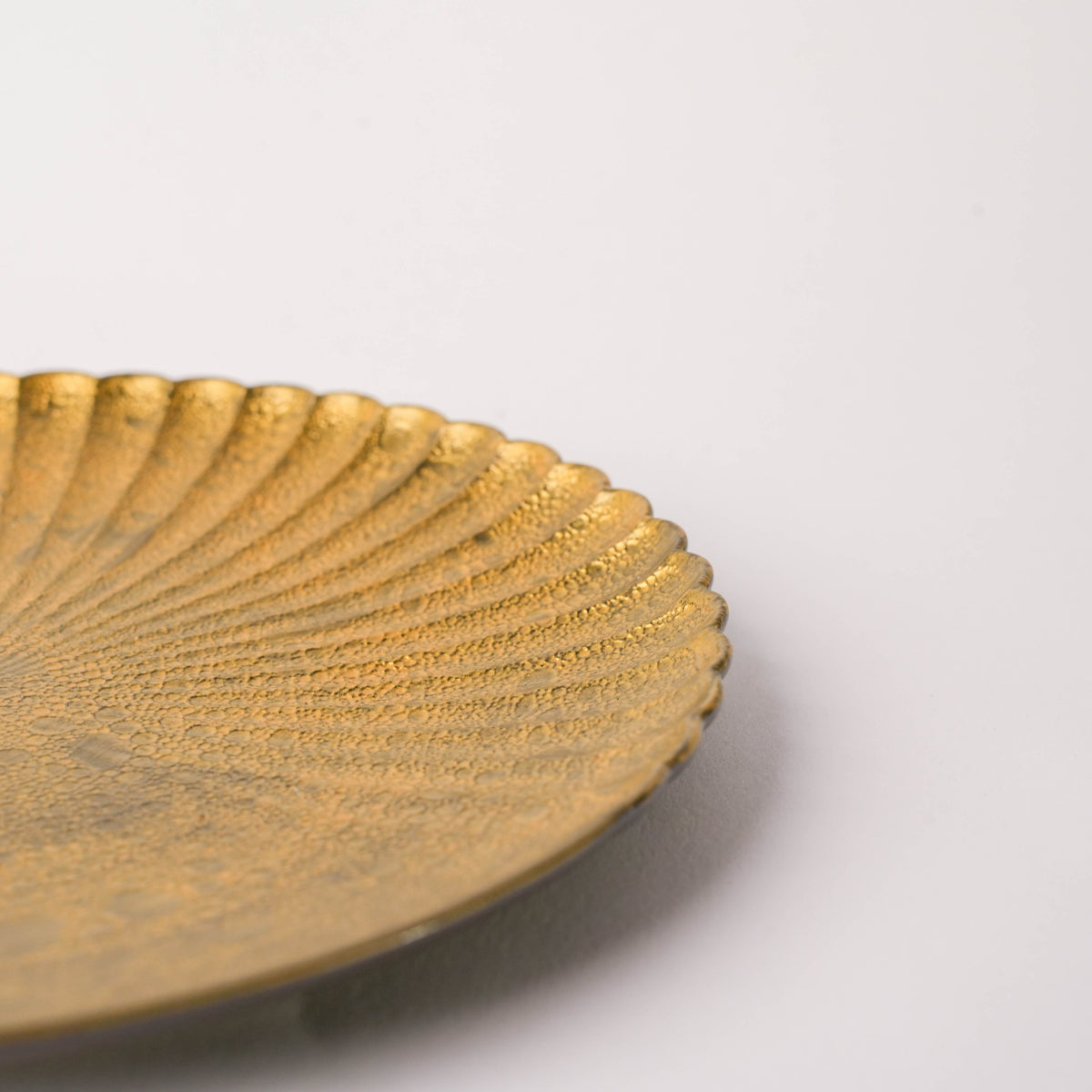 Detailed view of the gold textured surface of a ceramic plate with bubble design and scalloped edge, part of Japanese tableware