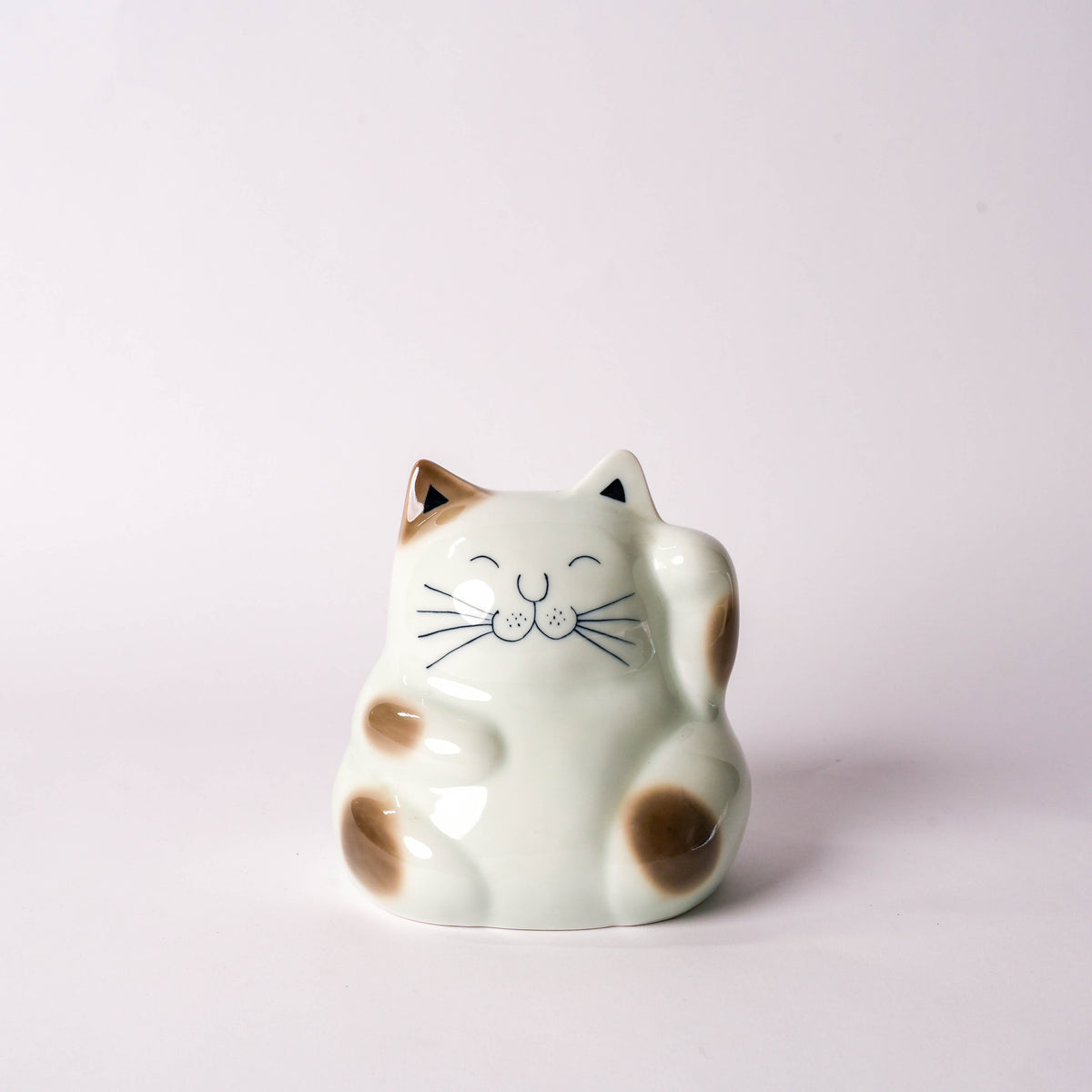 White ceramic cat figurine with black facial features and brown spots, sitting on a plain white background, decorative home decor